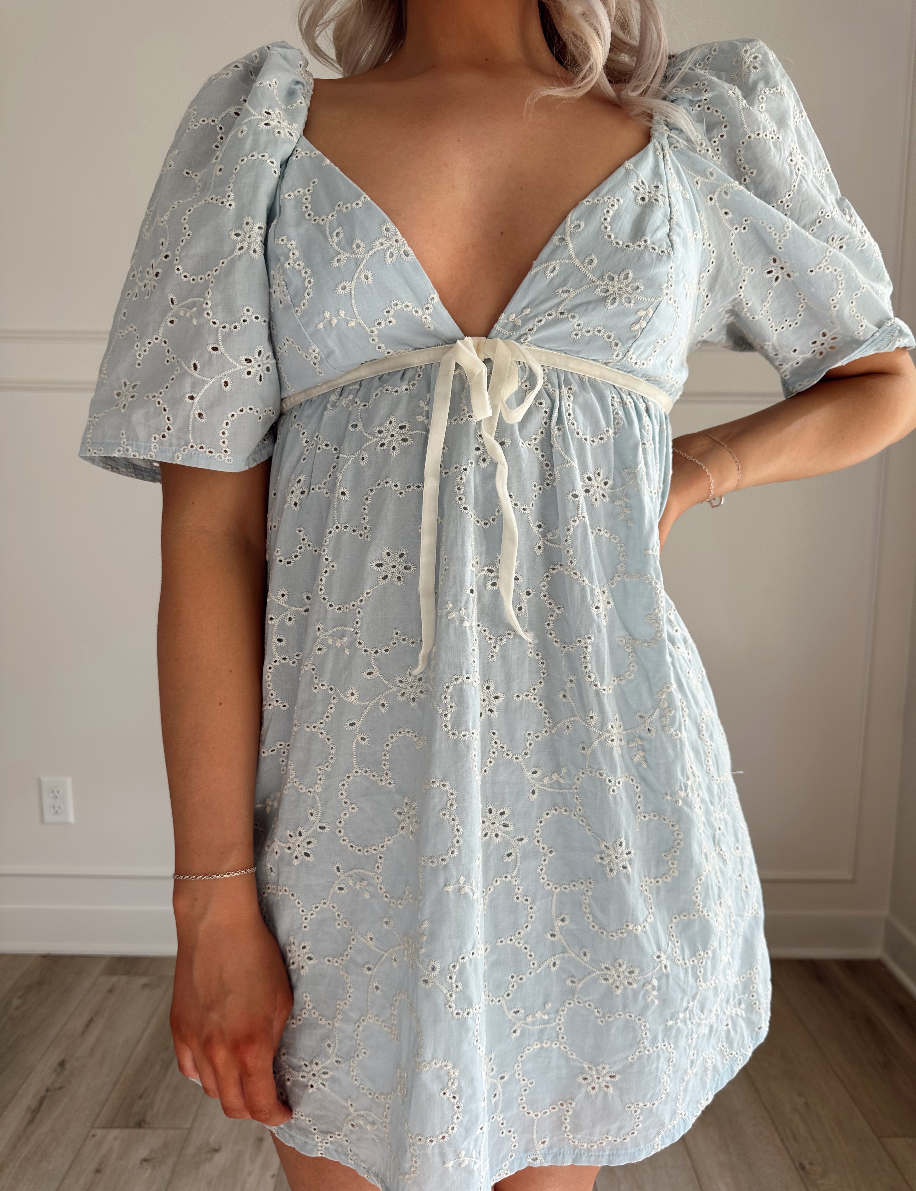 Light blue eyelet mini dress with puff sleeves and a tie-front detail.
