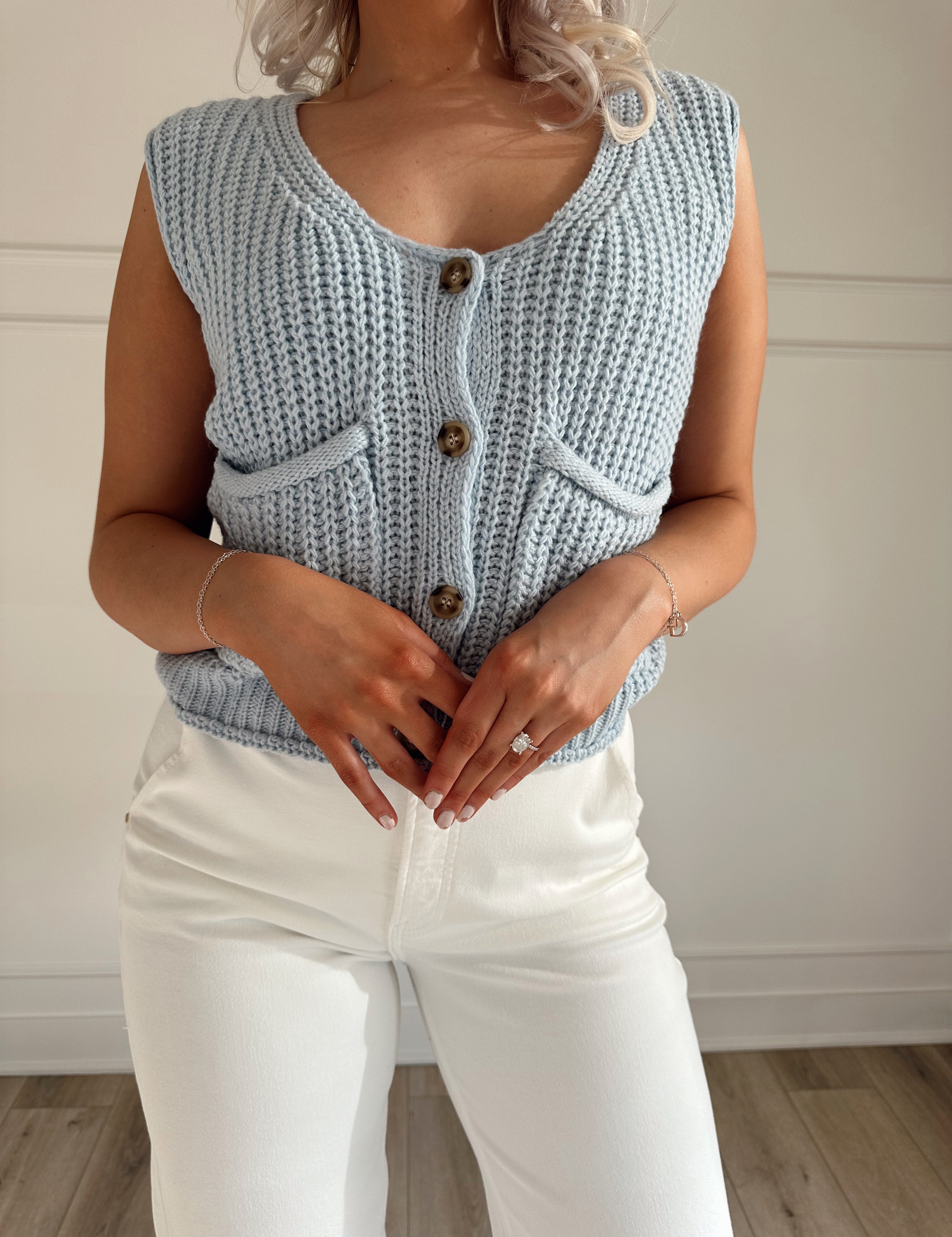 Baby blue chunky knit vest with functional pockets and button closure. 