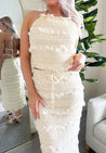 Woman wearing ivory two piece set with halter tie back top and smocked ruffled midi skirt