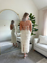 Woman wearing ivory two piece set with halter tie back top and smocked ruffled midi skirt