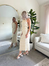 Woman wearing ivory two piece set with halter tie back top and smocked ruffled midi skirt