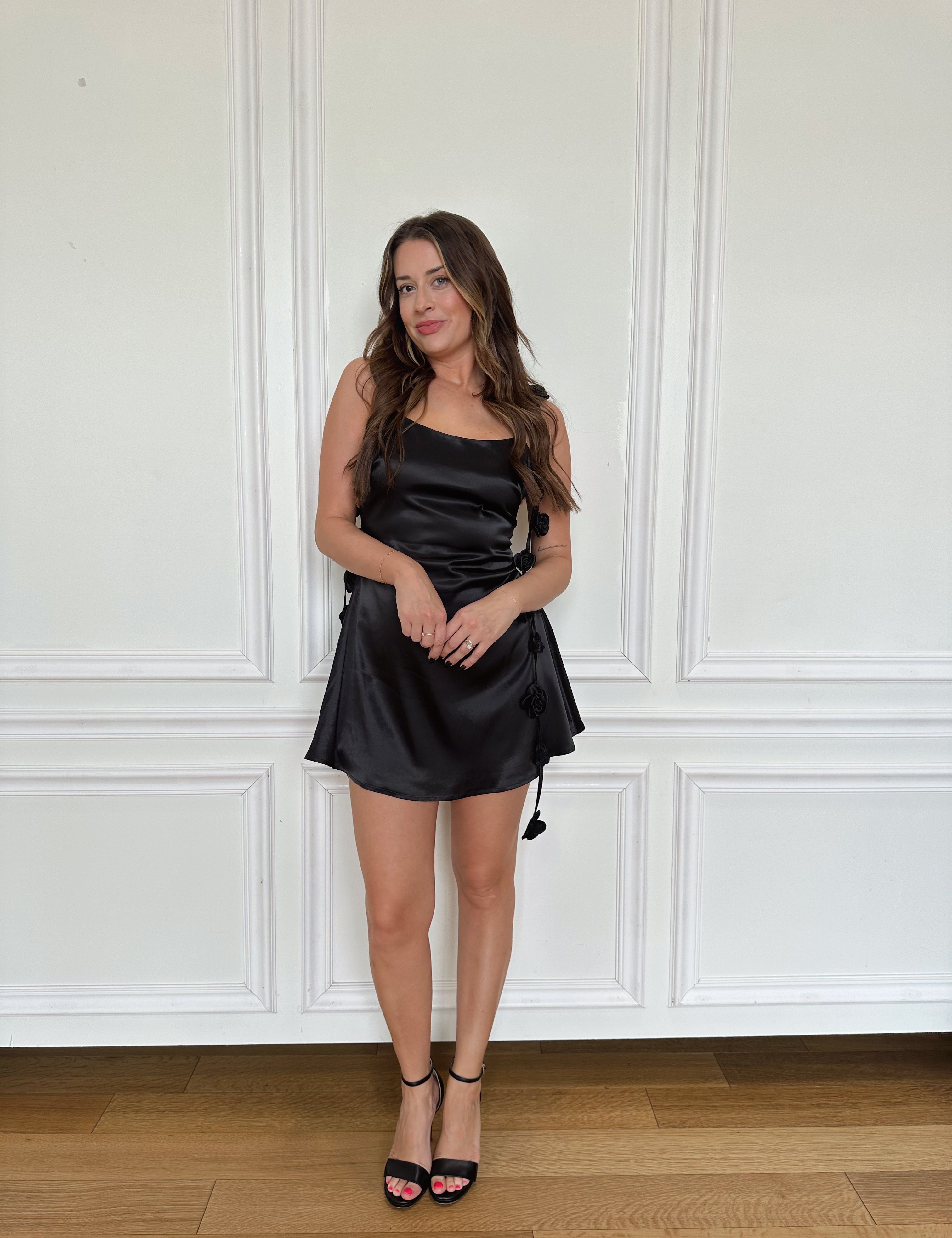 Black satin mini dress with long rosette detail straps. Perfect for special occasions. 