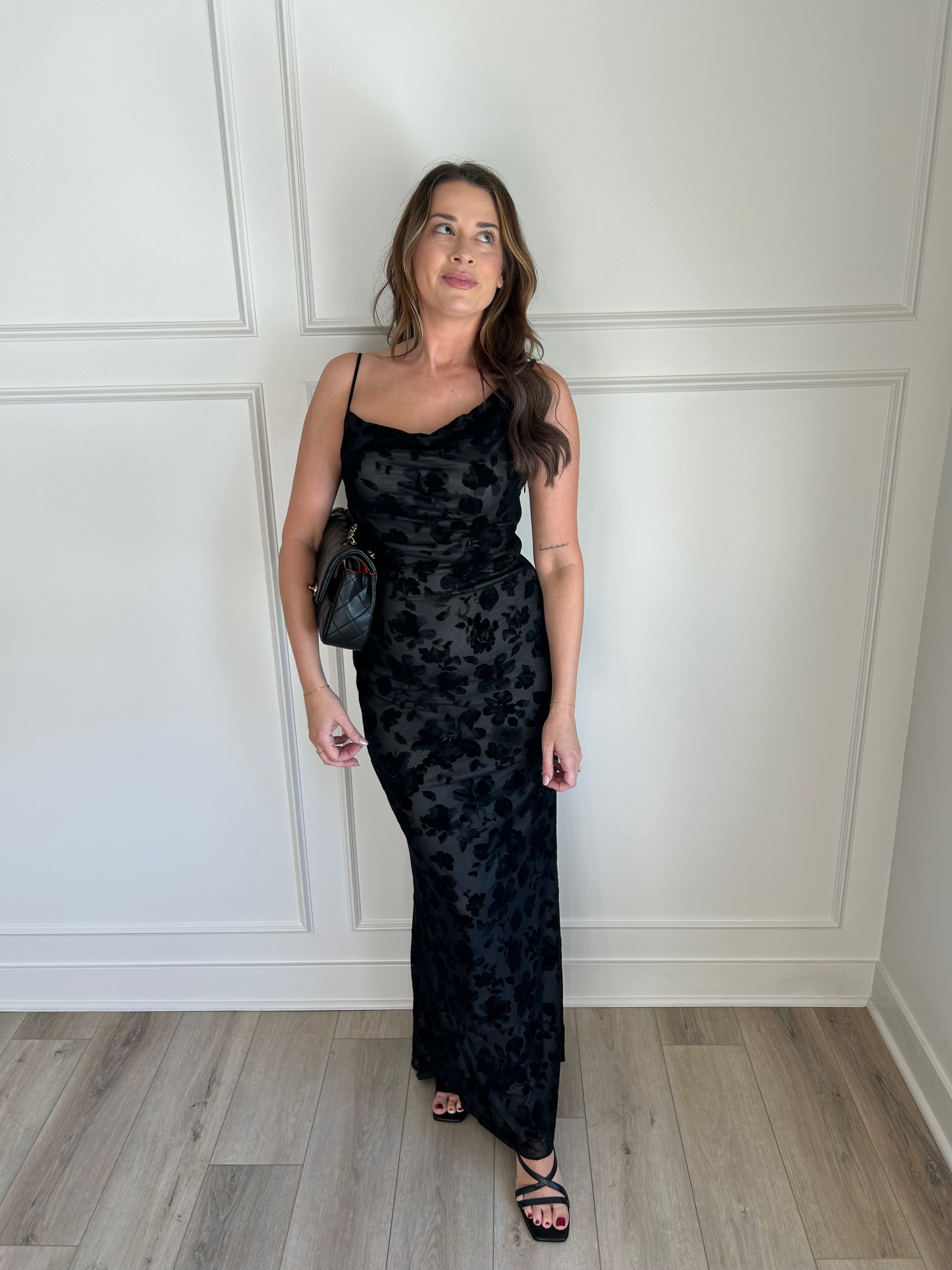 Black floral velvet maxi dress with spaghetti straps, cowl neckline, and sheer detailing for elegance.