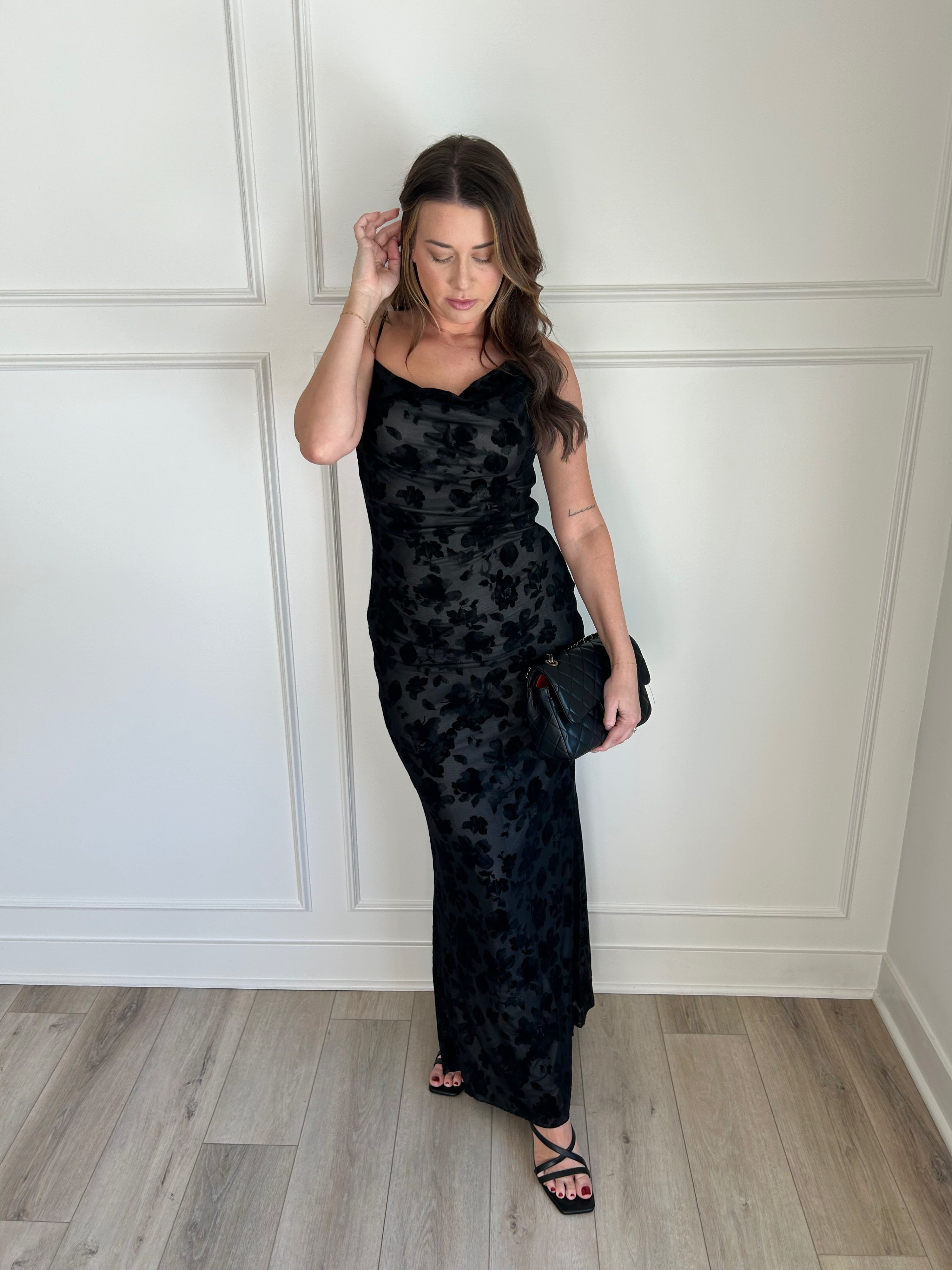 Black floral velvet maxi dress with spaghetti straps, cowl neckline, and sheer detailing for elegance.