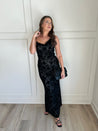 Black floral velvet maxi dress with spaghetti straps, cowl neckline, and sheer detailing for elegance.