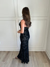 Black floral velvet maxi dress with spaghetti straps, cowl neckline, and sheer detailing for elegance.