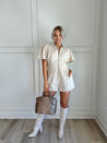 Beige eyelet romper with puff sleeves, zip-front closure, and functional pockets for stylish convenience.