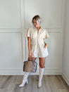 Beige eyelet romper with puff sleeves, zip-front closure, and functional pockets for stylish convenience.