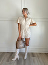 Beige eyelet romper with puff sleeves, zip-front closure, and functional pockets for stylish convenience.