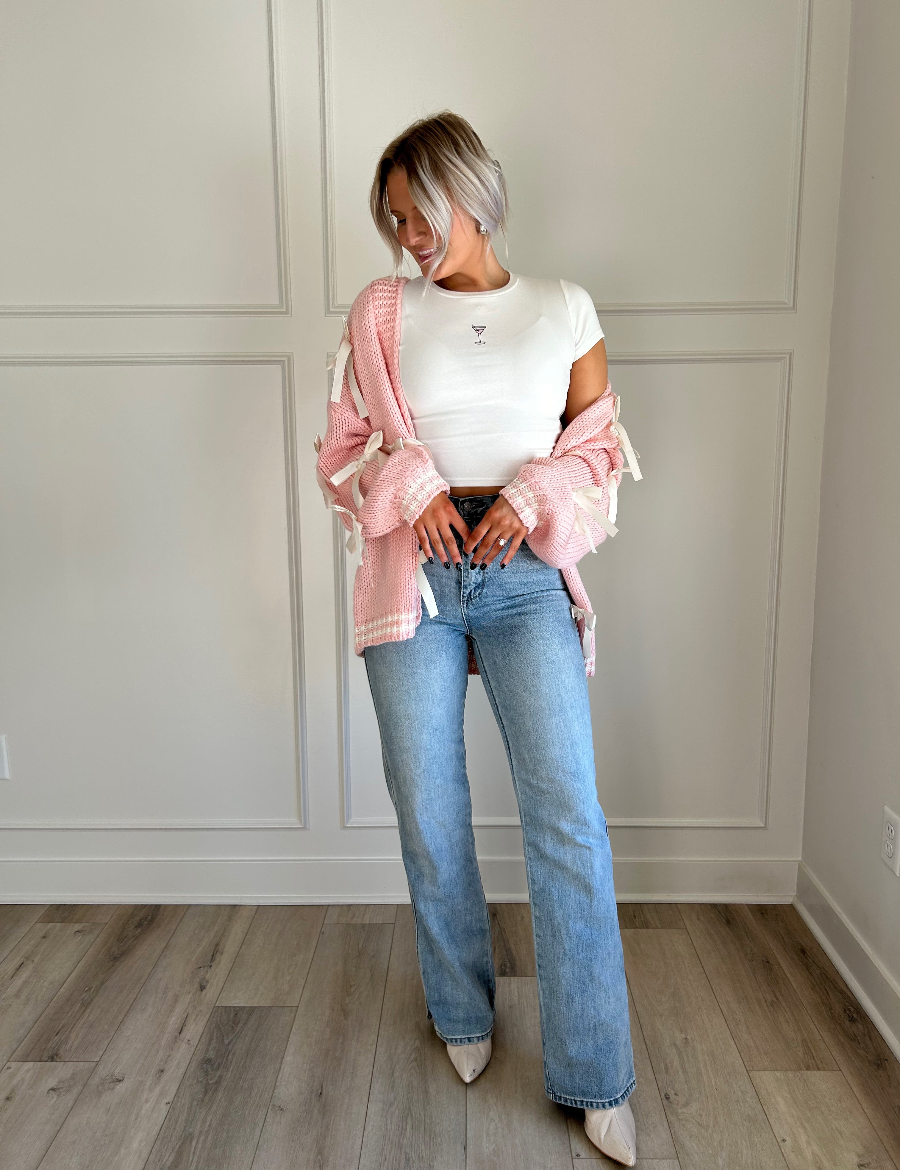 Pink knit cardigan with satin ribbon details and oversized cozy design.