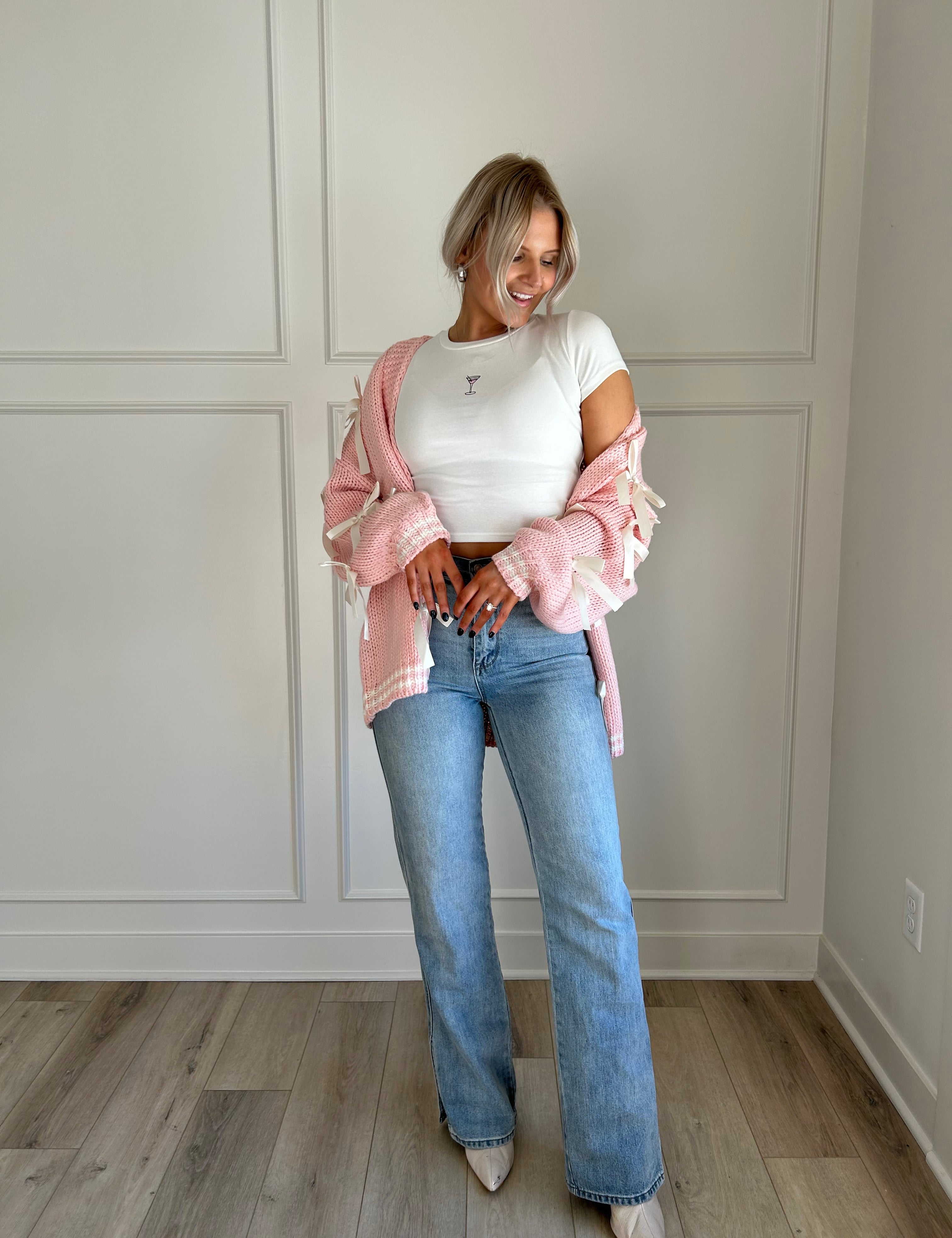 Pink knit cardigan with satin ribbon details and oversized cozy design.