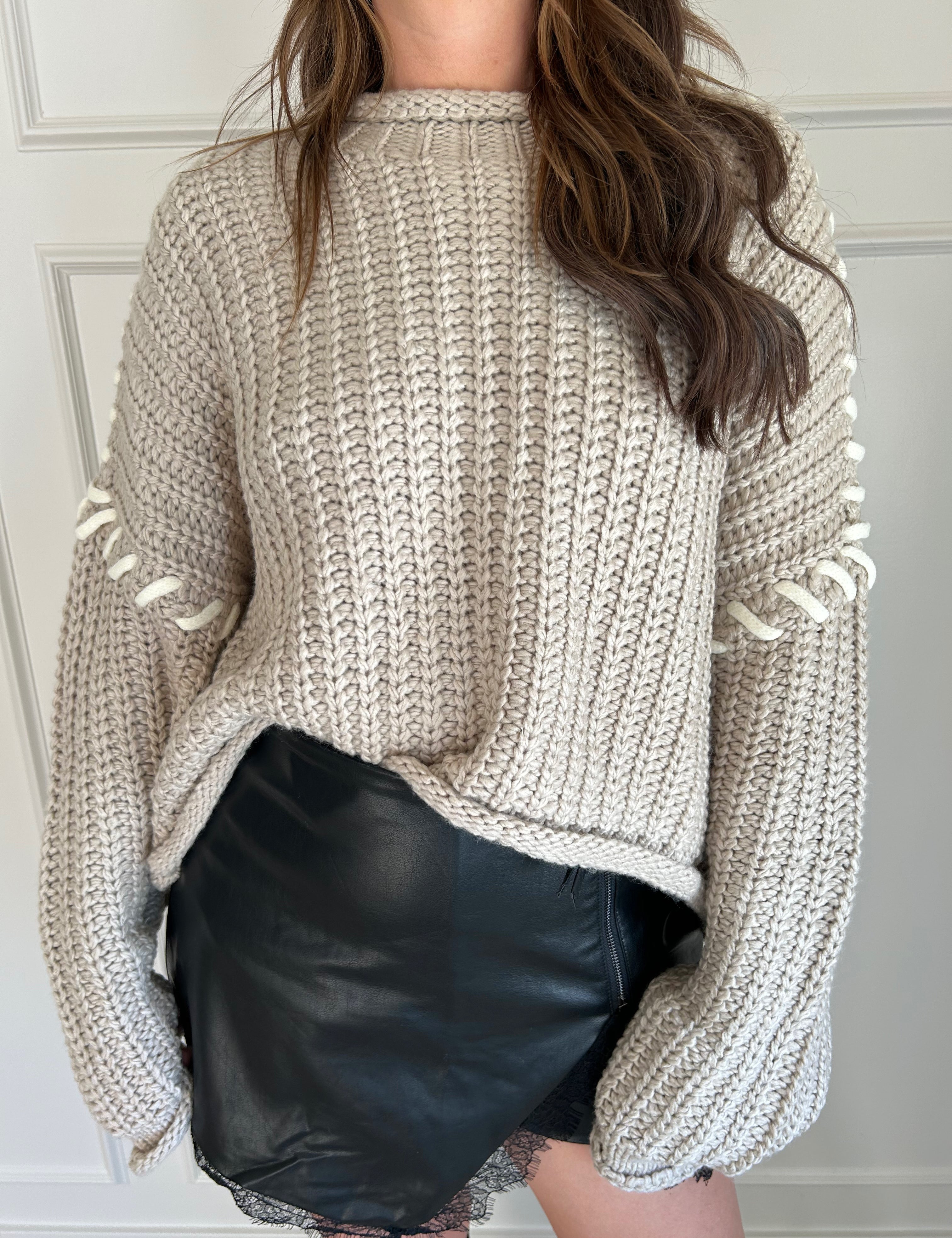 Beige chunky knit sweater with lace-up sleeve details and cozy fit.