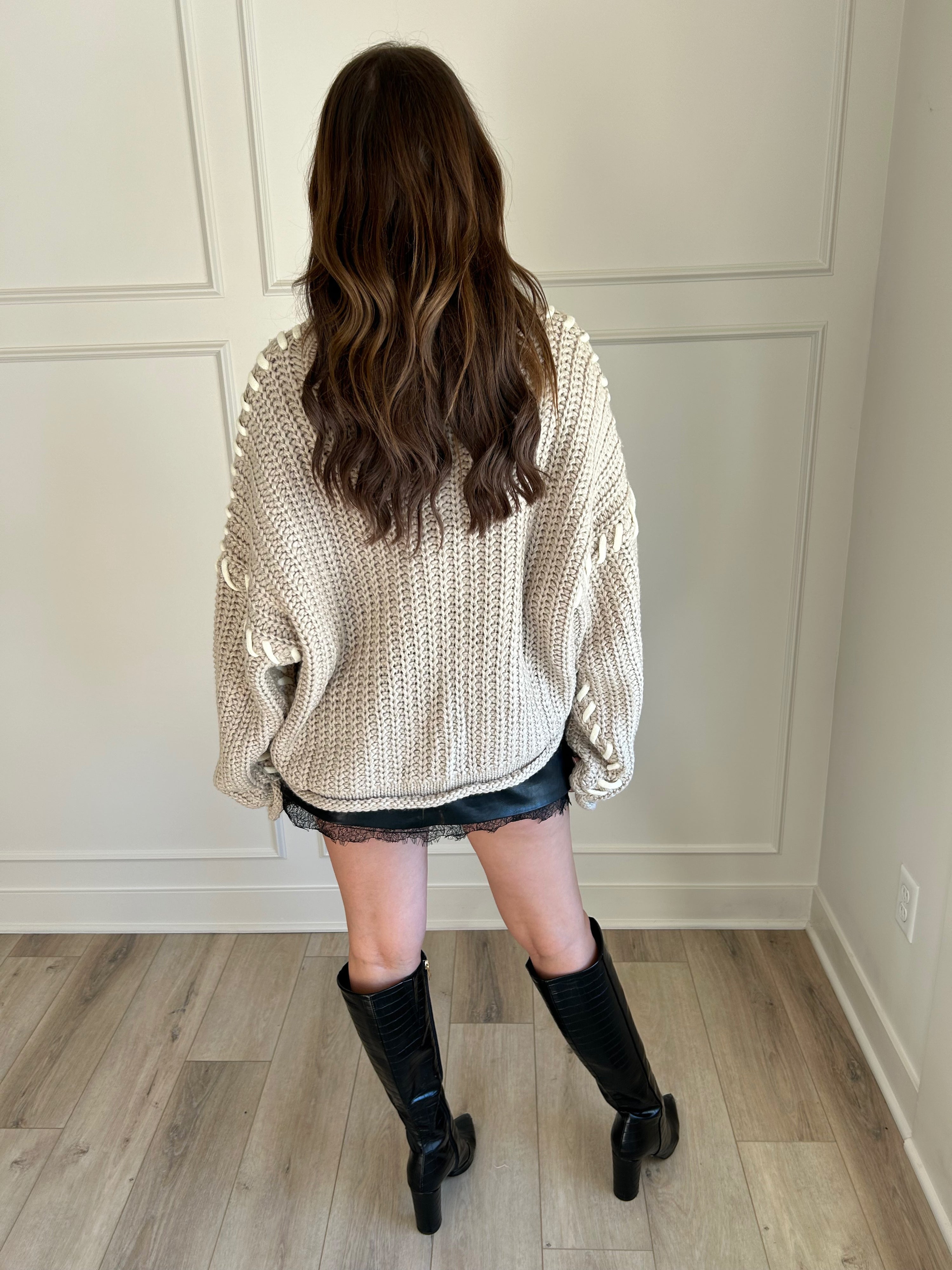 Beige chunky knit sweater with lace-up sleeve details and cozy fit.