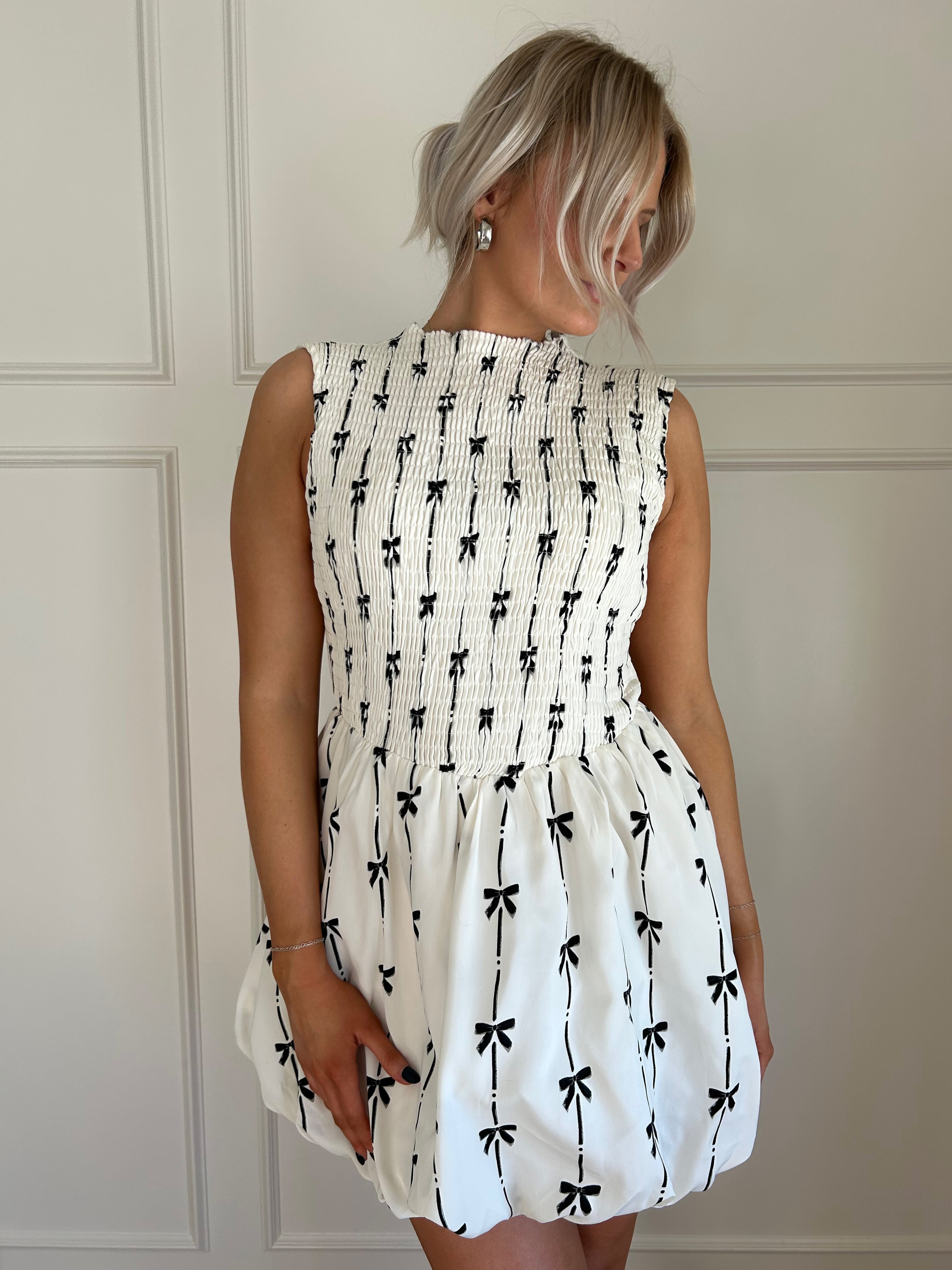 White bubble hem dress with black bow embroidery and smocked bodice.