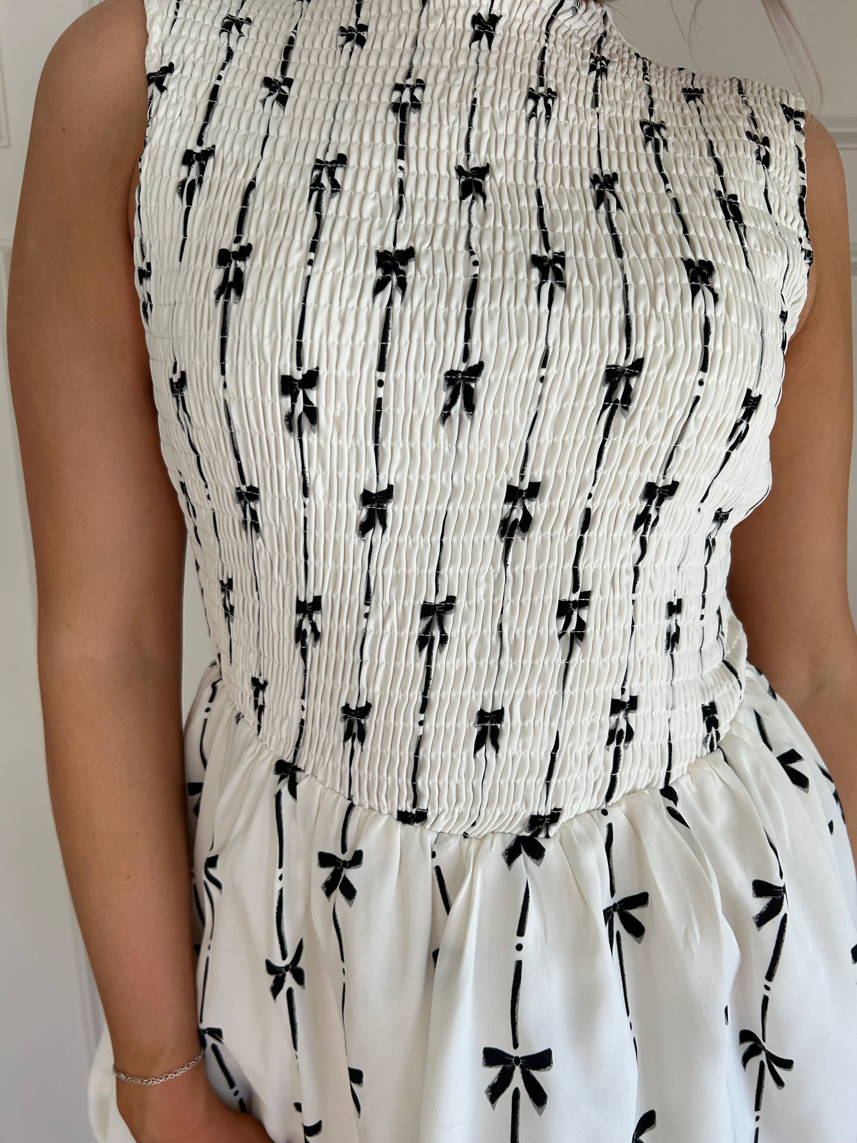 White bubble hem dress with black bow embroidery and smocked bodice.