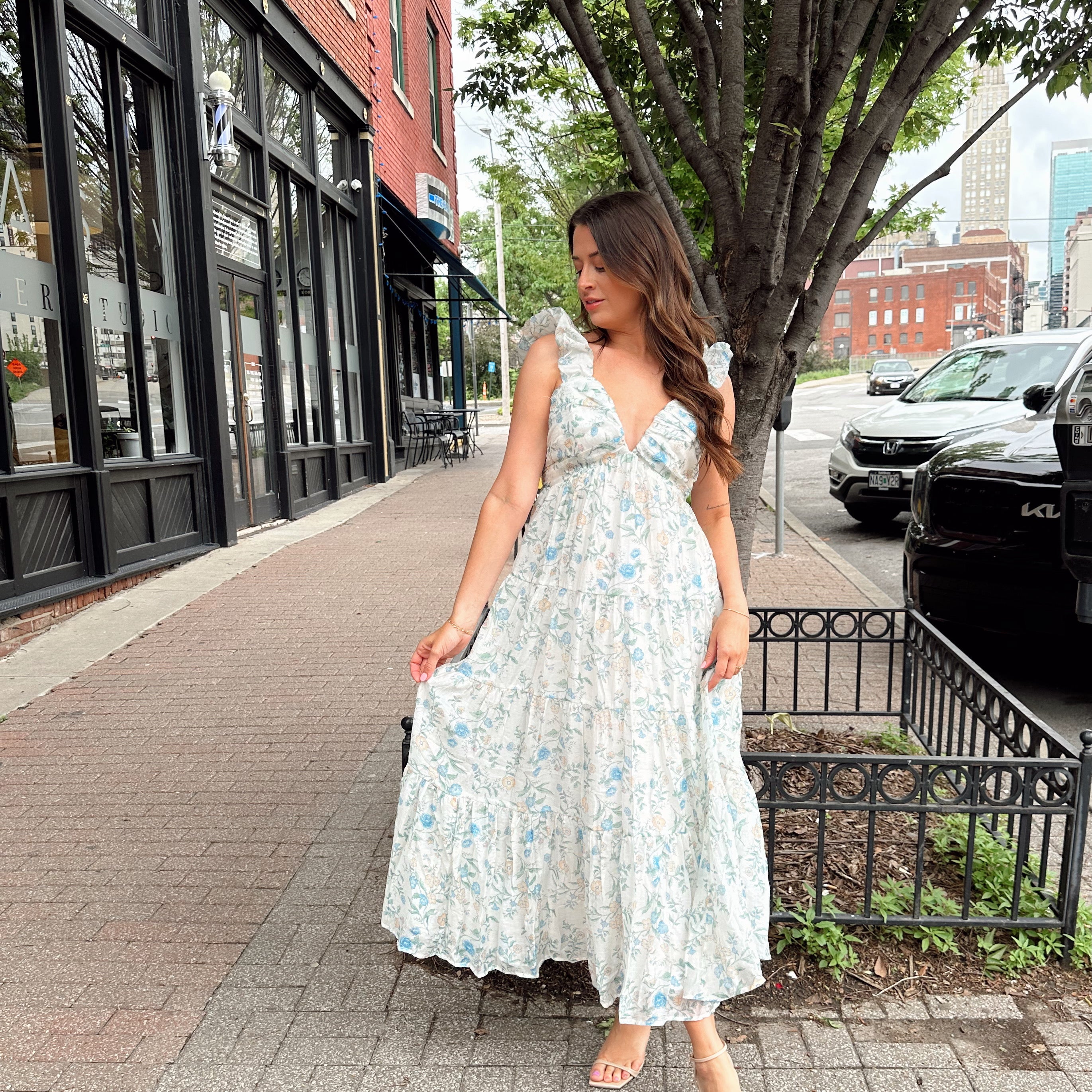 Woman in a blue floral maxi dress with ruffle straps, v-neck, and tiered skirt