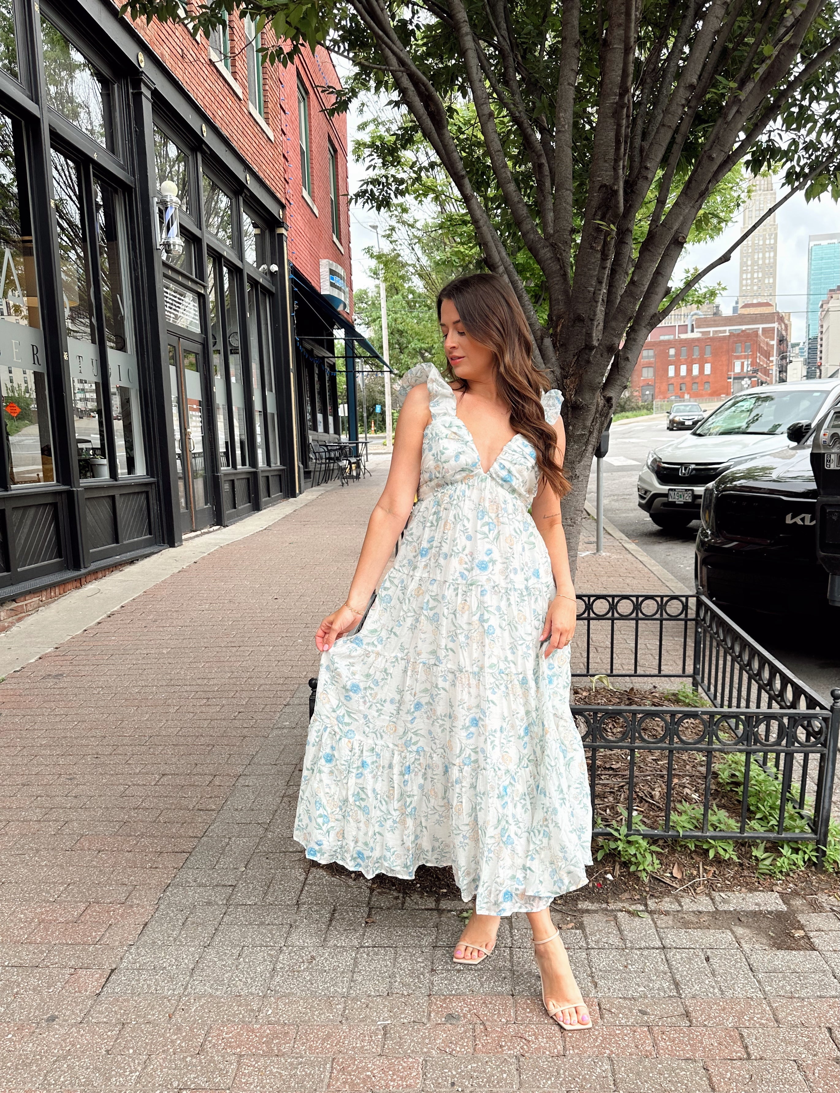 Woman in a blue floral maxi dress with ruffle straps, v-neck, and tiered skirt