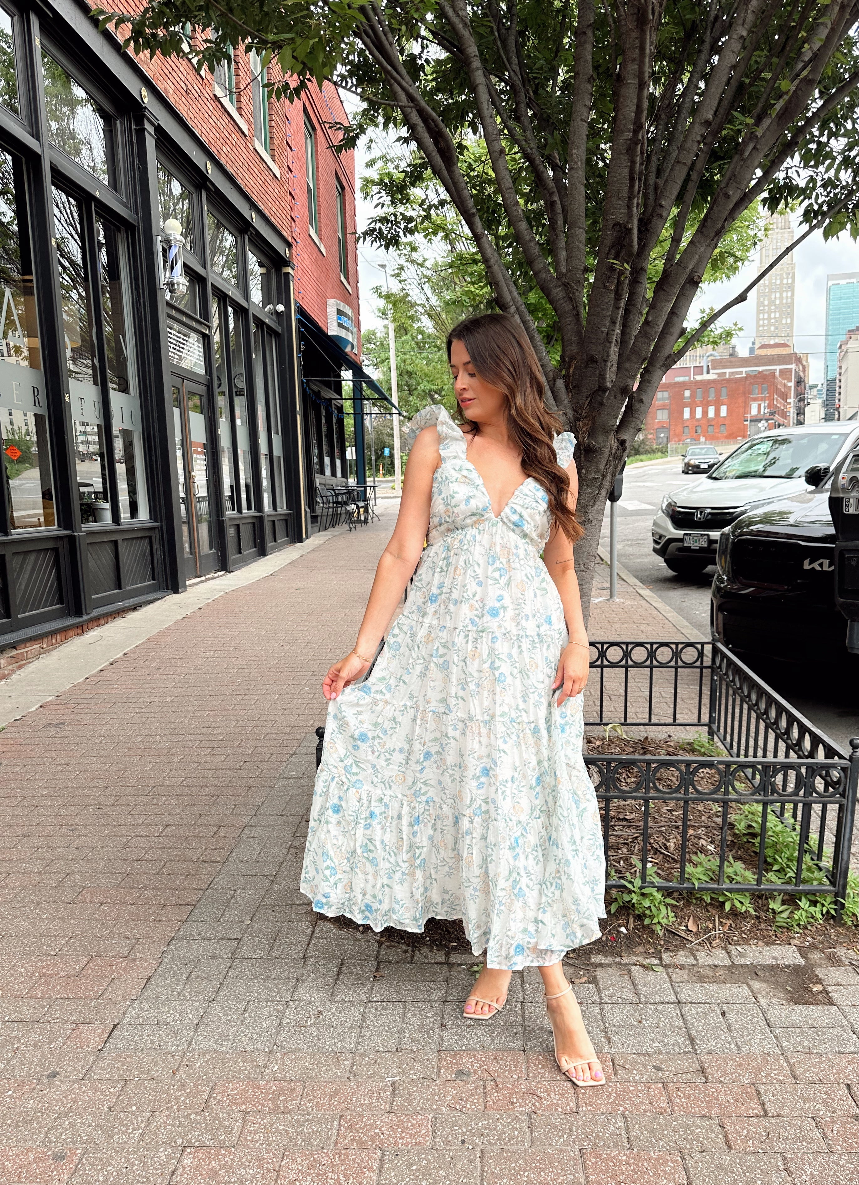 Woman in a blue floral maxi dress with ruffle straps, v-neck, and tiered skirt
