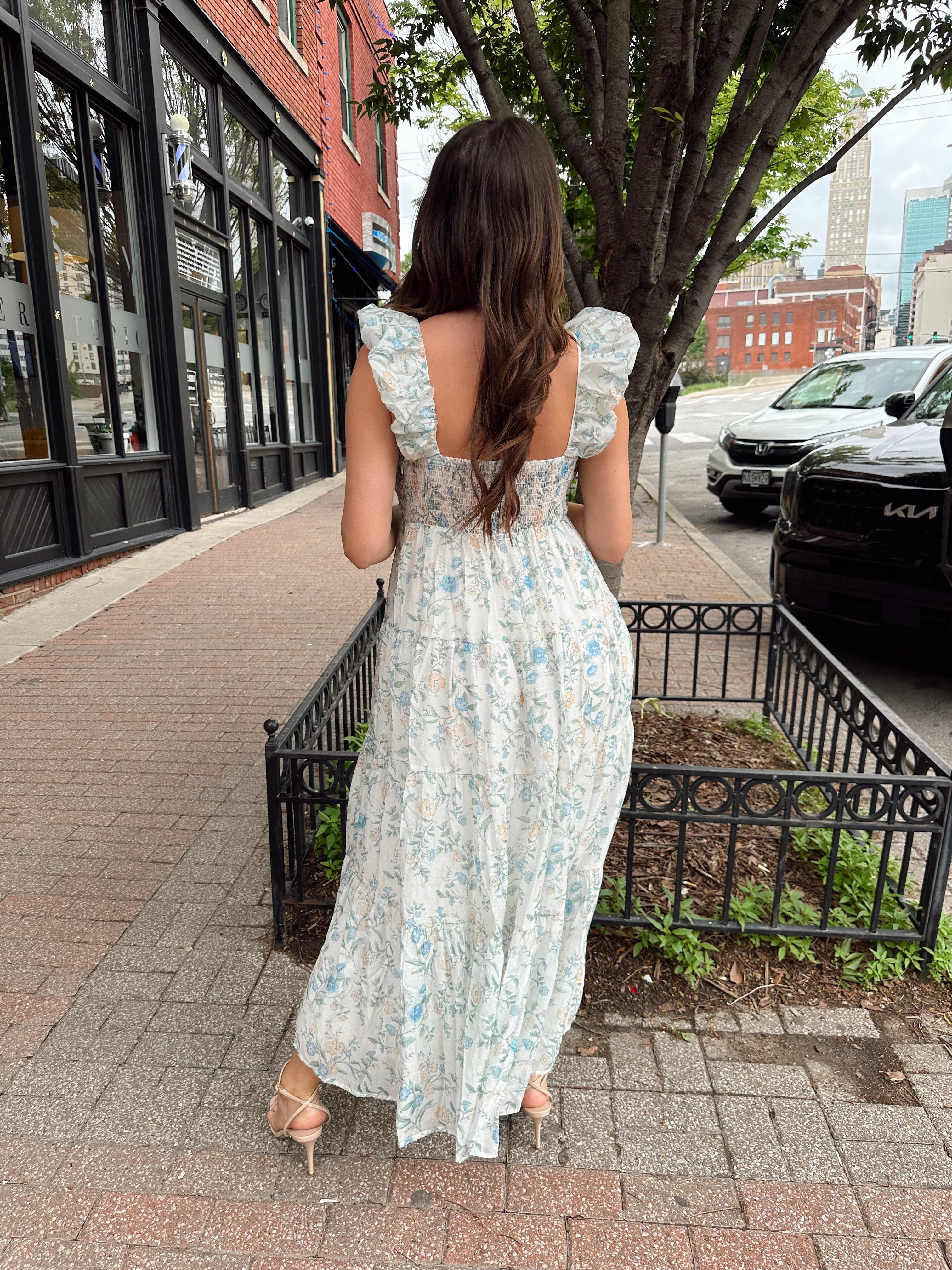 Woman in a blue floral maxi dress with ruffle straps, v-neck, and tiered skirt