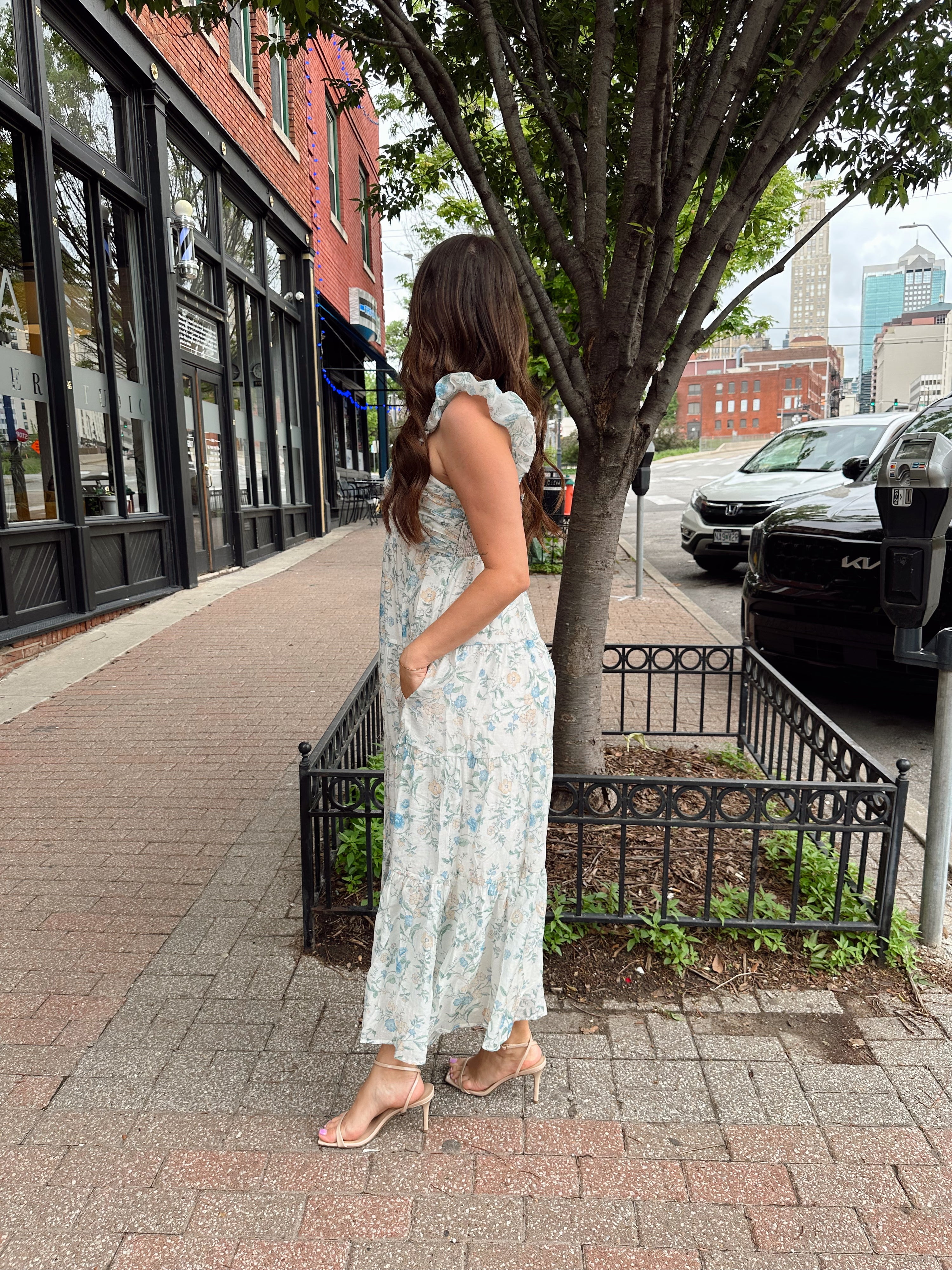 Woman in a blue floral maxi dress with ruffle straps, v-neck, and tiered skirt