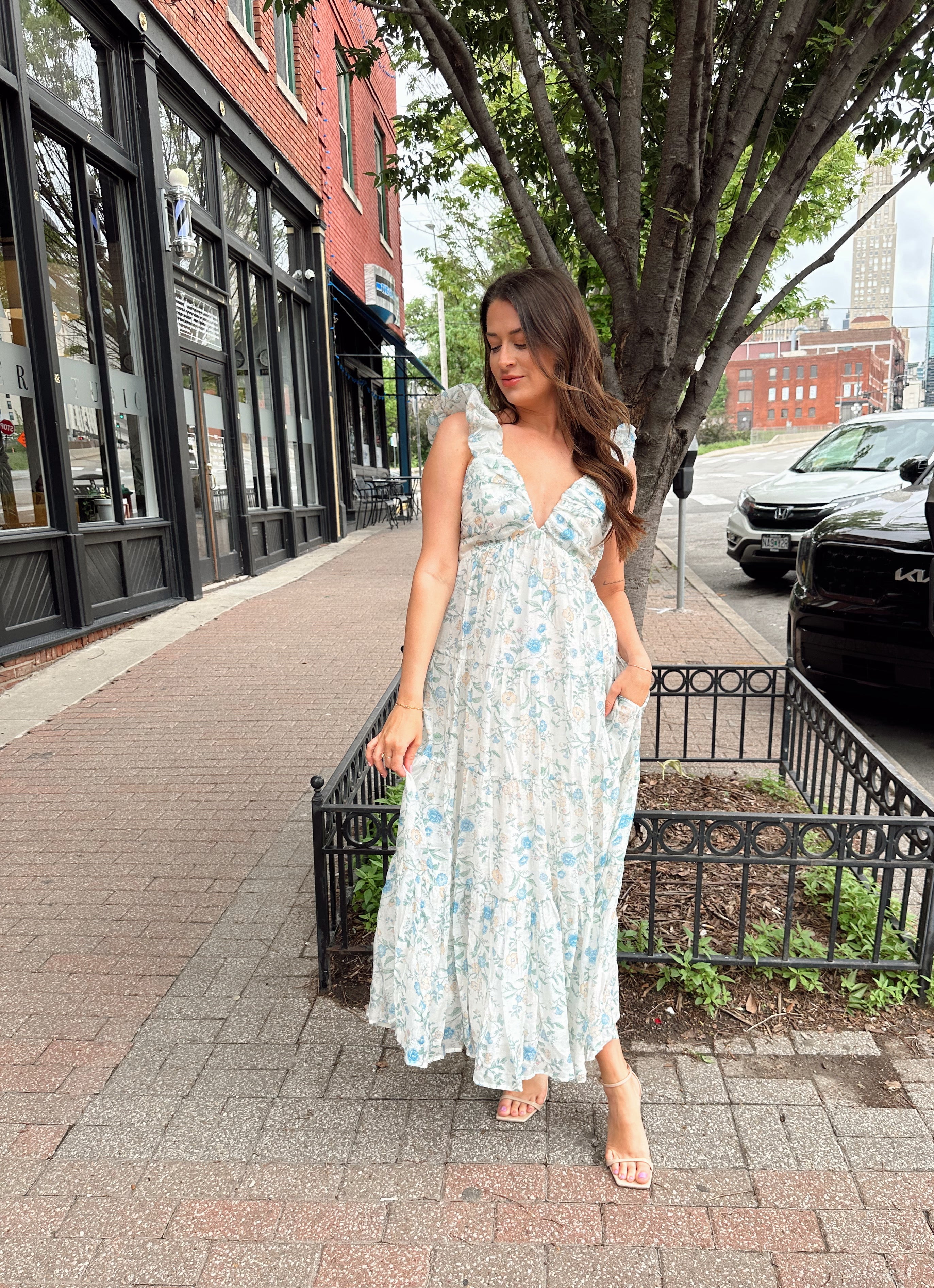 Woman in a blue floral maxi dress with ruffle straps, v-neck, and tiered skirt