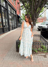 Woman in a blue floral maxi dress with ruffle straps, v-neck, and tiered skirt