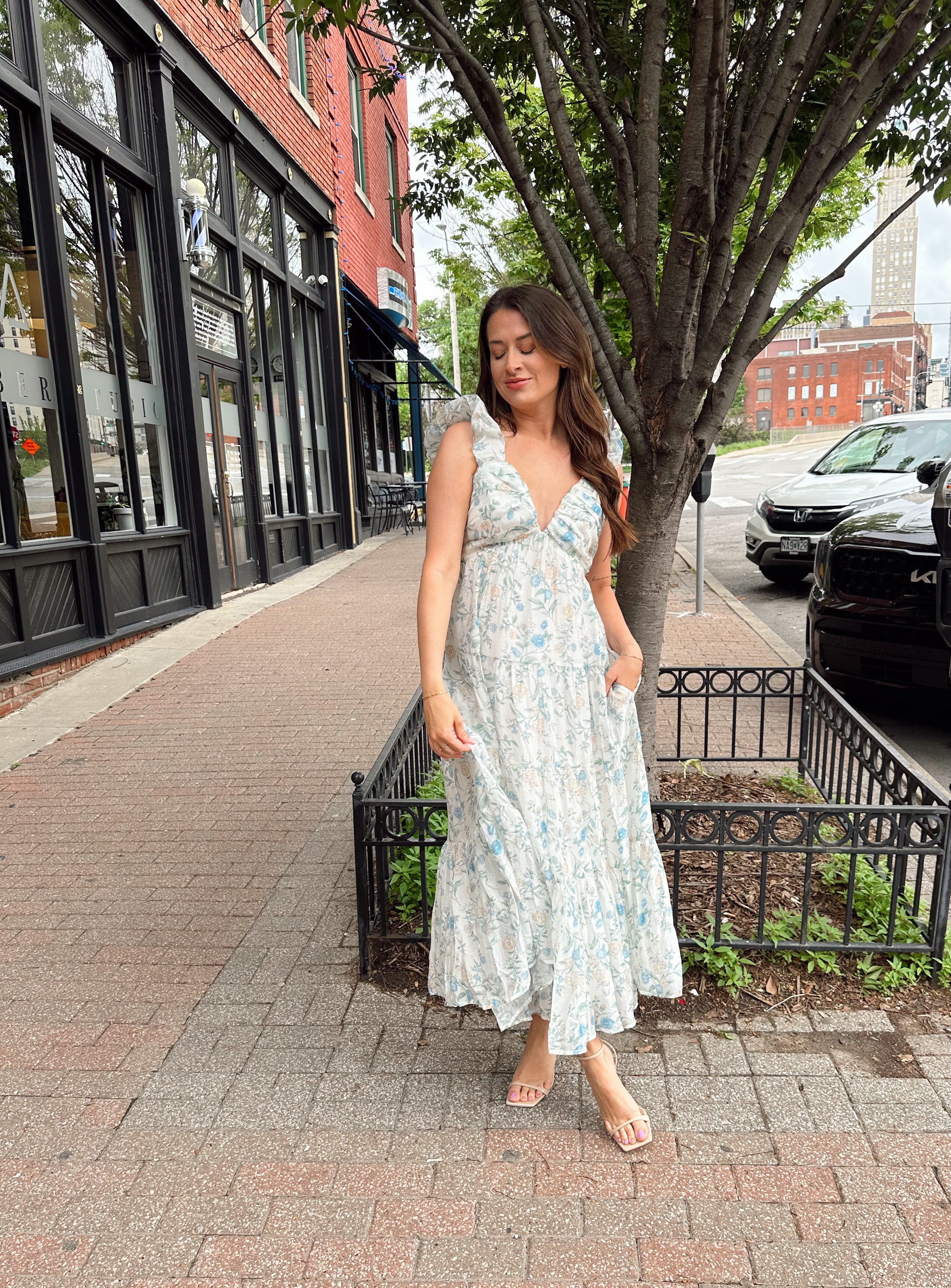 Woman in a blue floral maxi dress with ruffle straps, v-neck, and tiered skirt