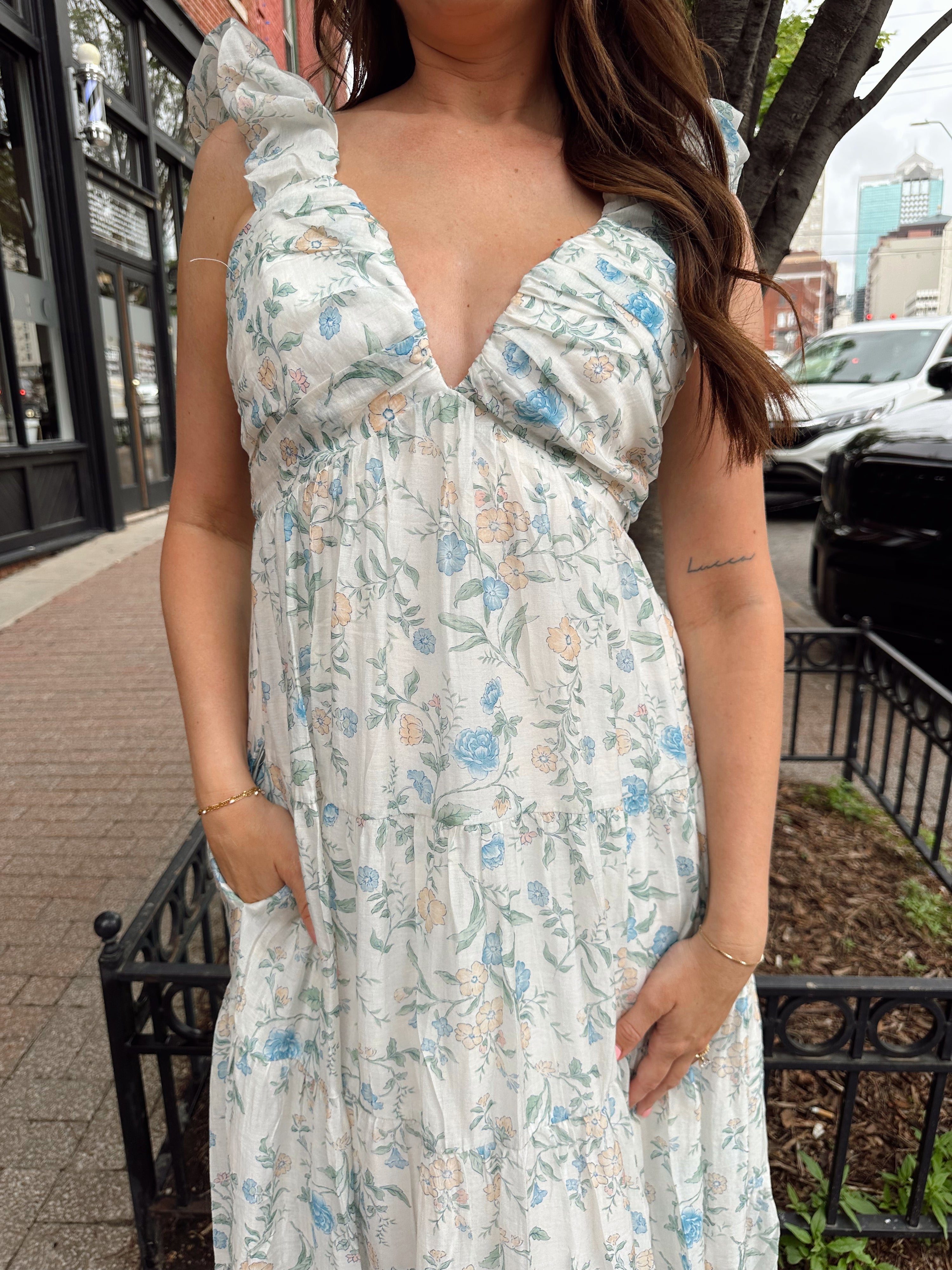 Woman in a blue floral maxi dress with ruffle straps, v-neck, and tiered skirt