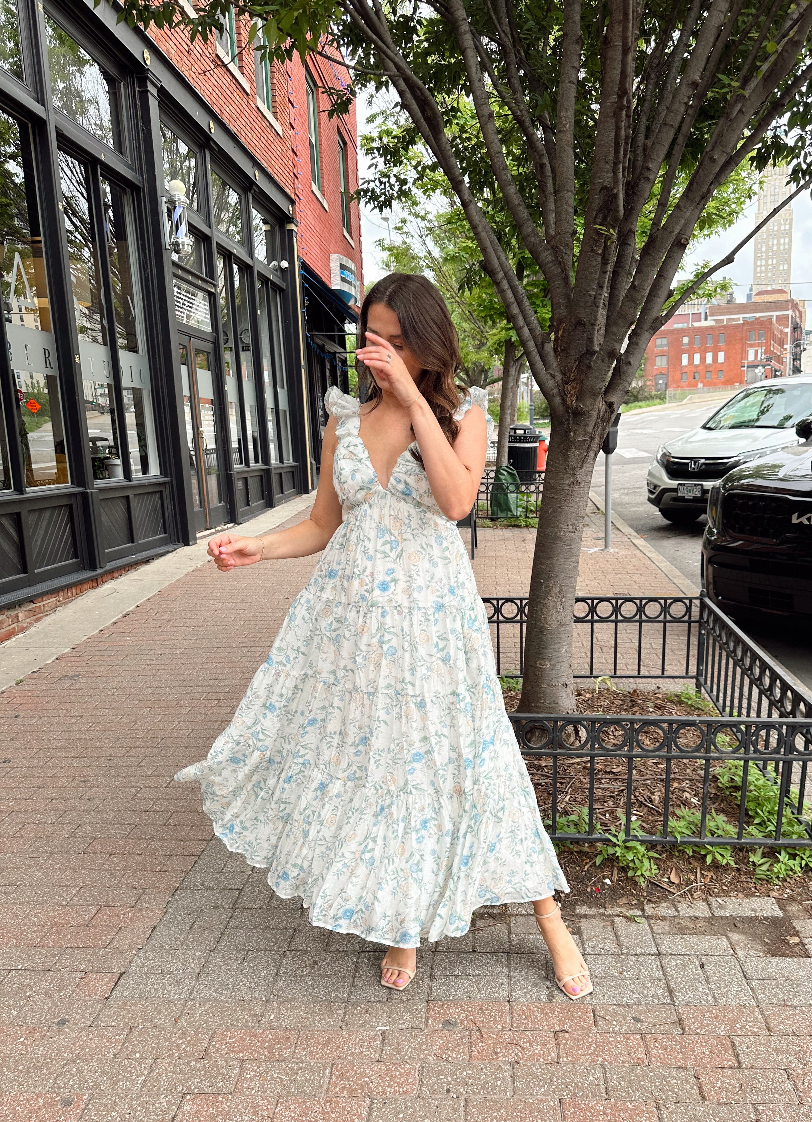 Woman in a blue floral maxi dress with ruffle straps, v-neck, and tiered skirt