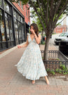 Woman in a blue floral maxi dress with ruffle straps, v-neck, and tiered skirt