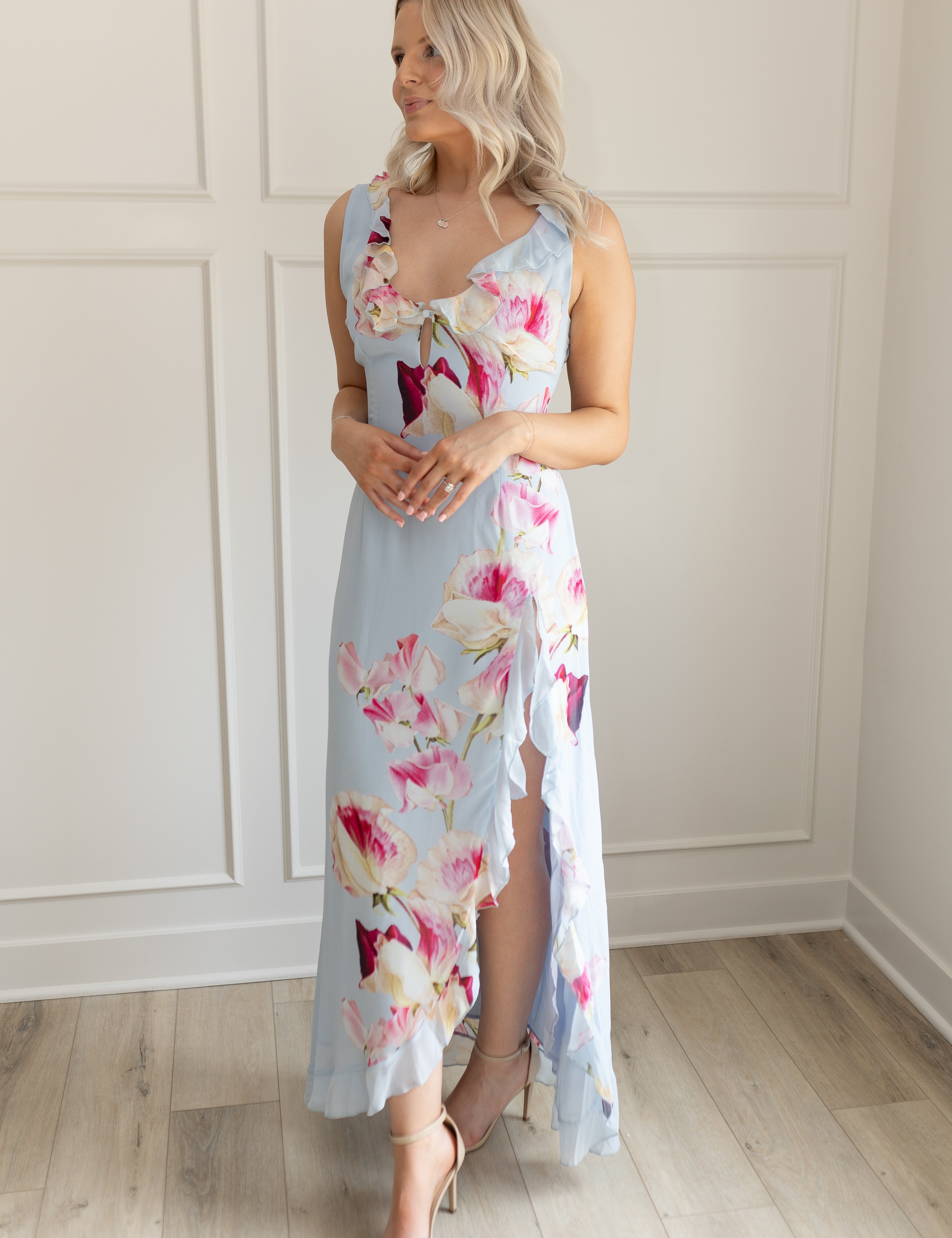 Blue maxi dress with pink floral pattern. Slit with a ruffle detail. 