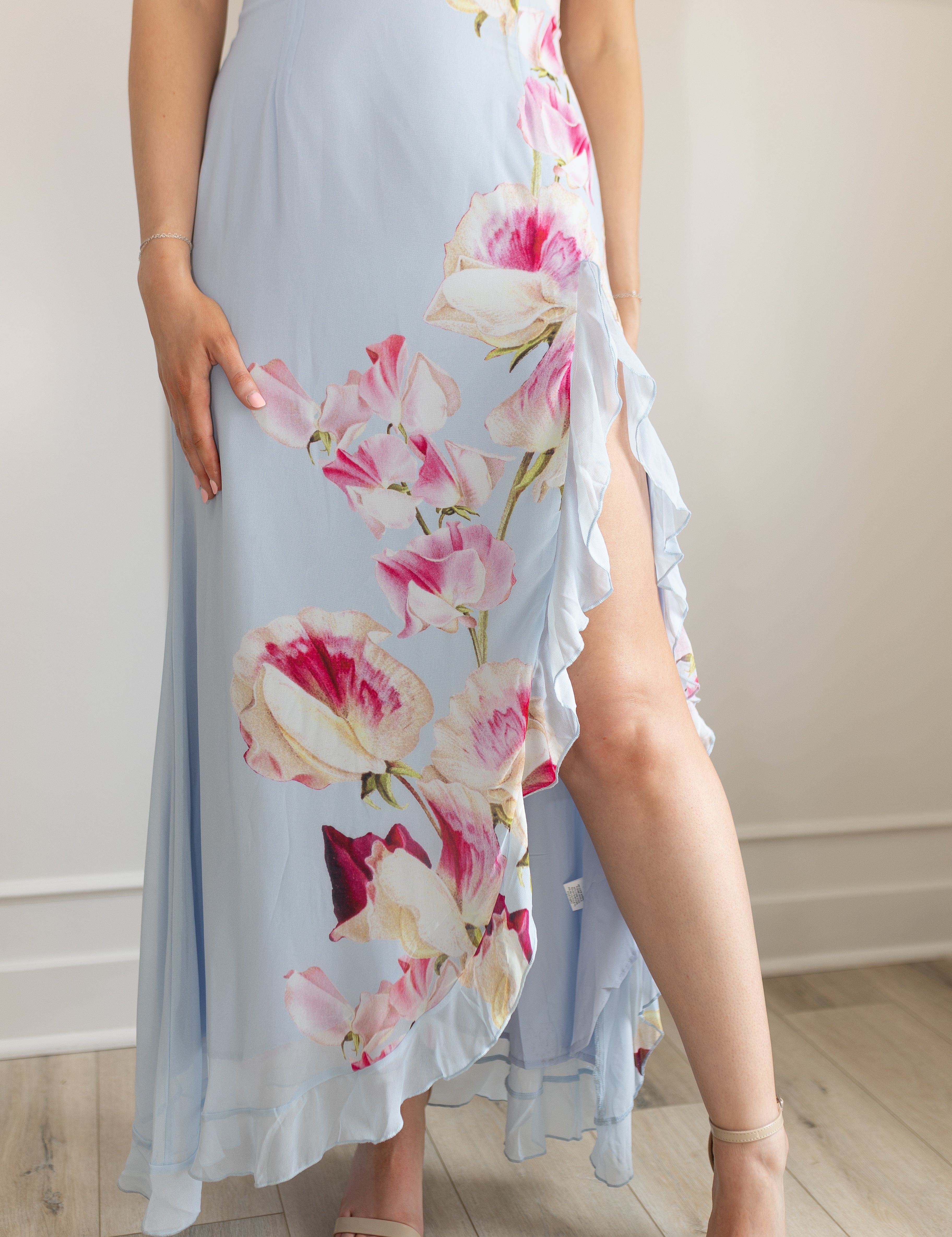 Blue maxi dress with pink floral pattern. Slit with a ruffle detail. 