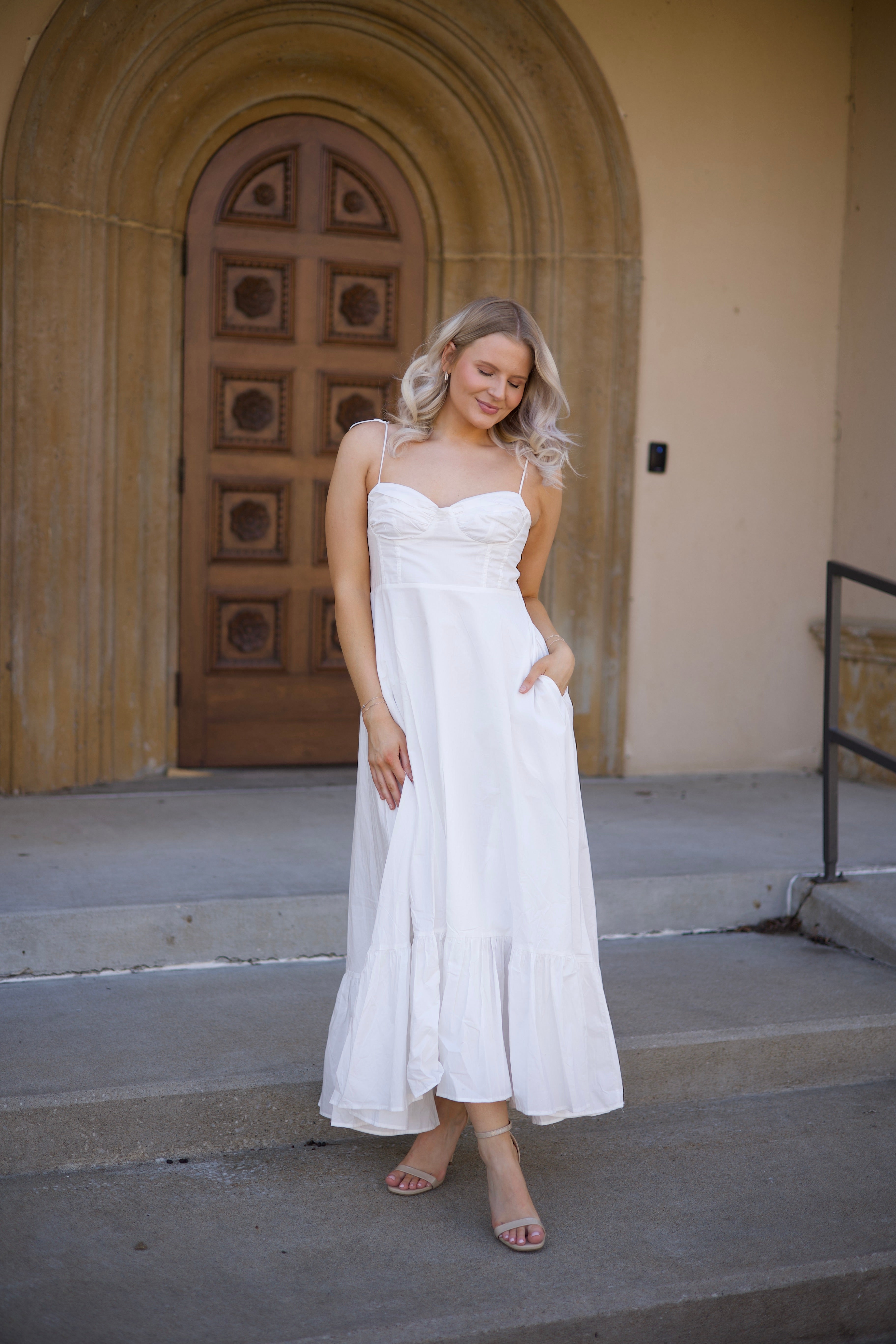Woman in white midi dress with tie straps, flounce hem.