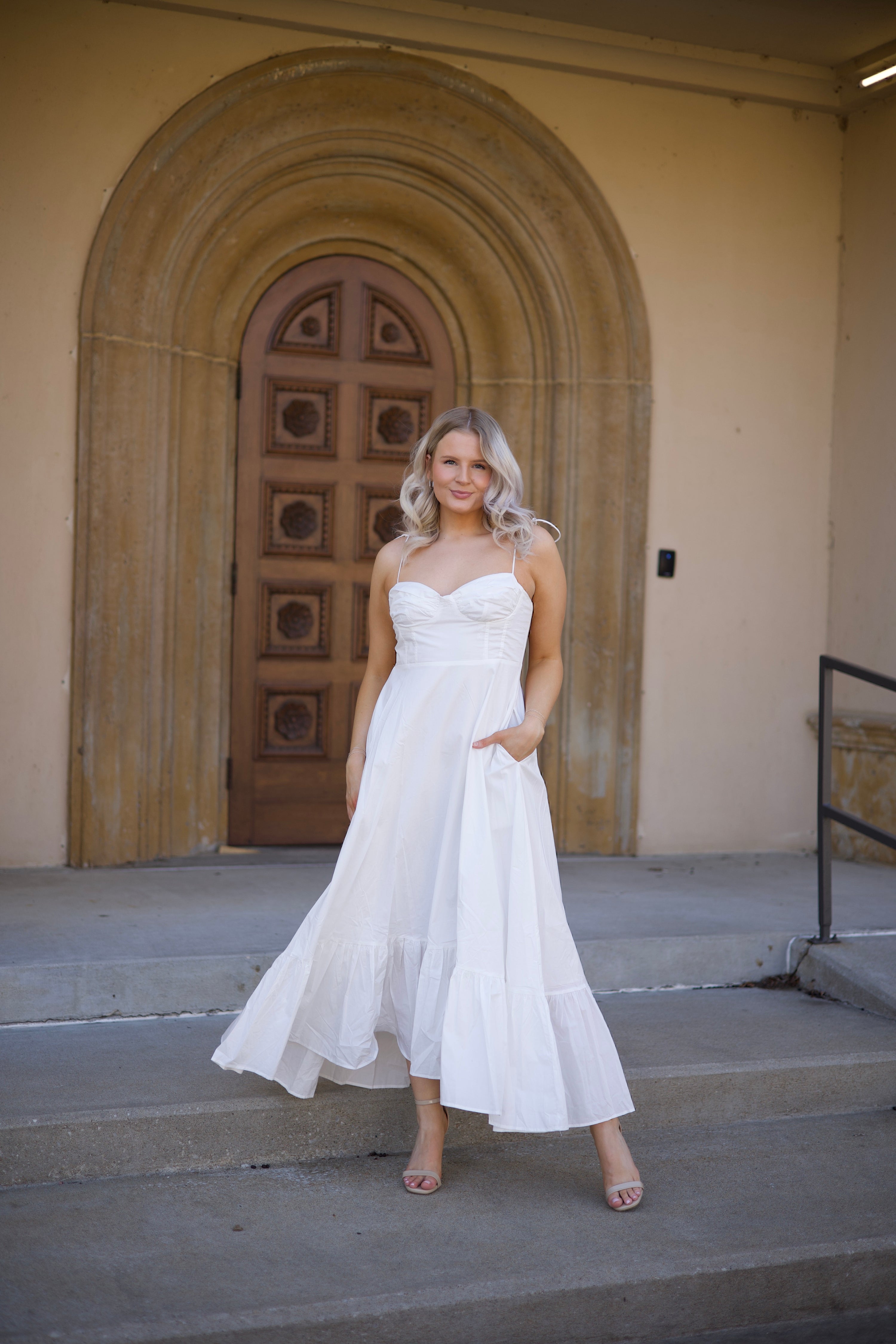 Woman in white midi dress with tie straps, flounce hem.