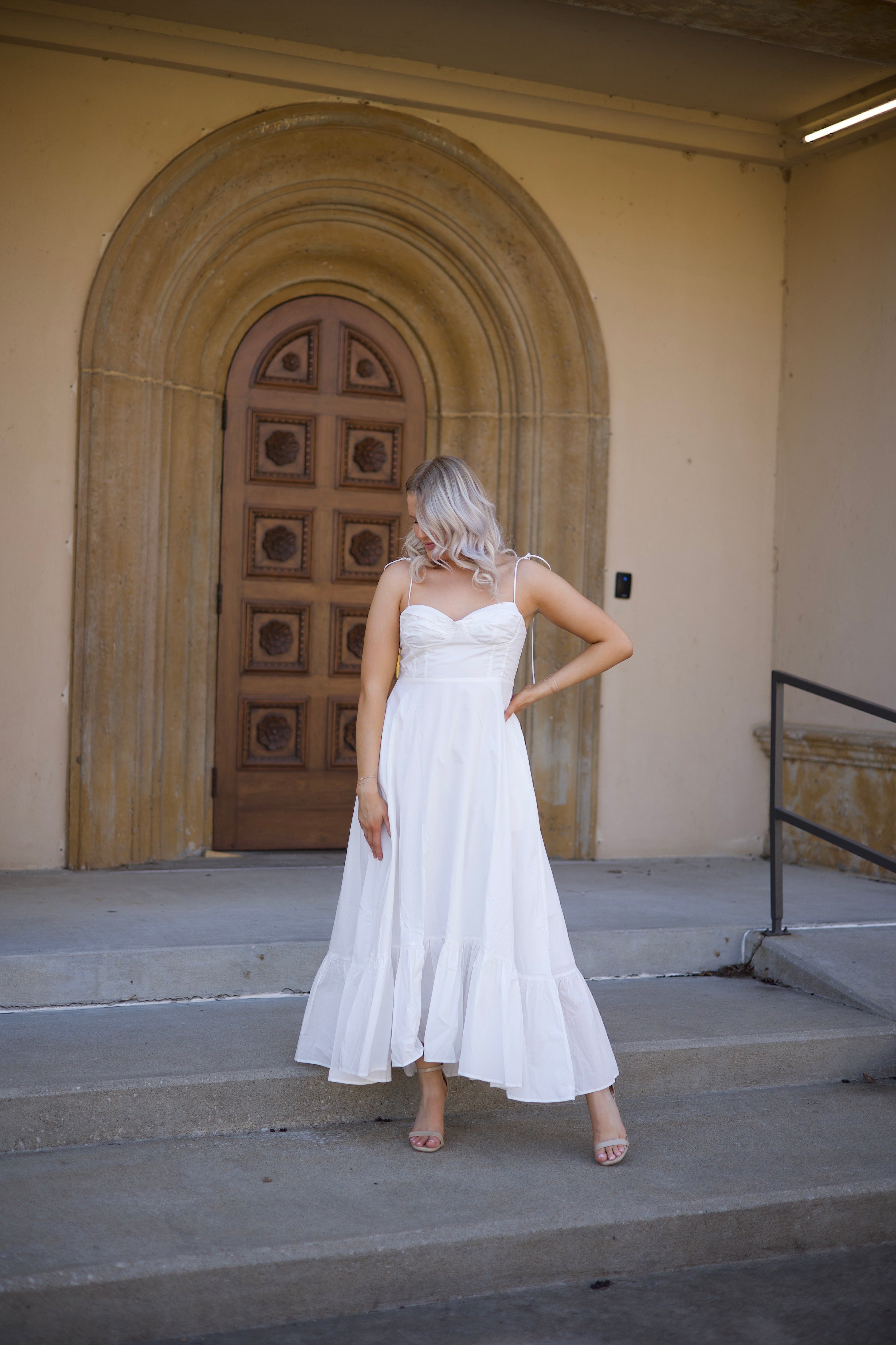 Woman in white midi dress with tie straps, flounce hem.