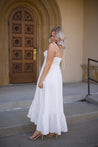 Woman in white midi dress with tie straps, flounce hem.