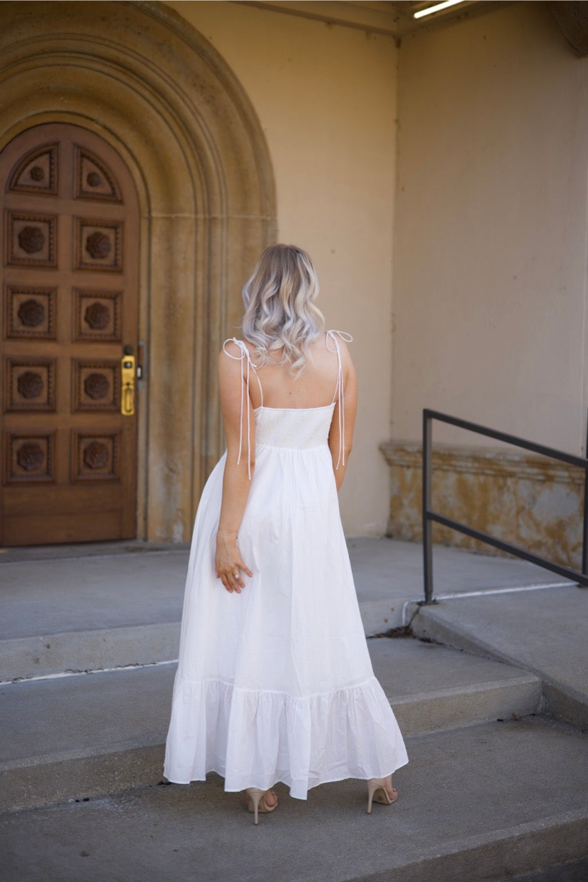 Woman in white midi dress with tie straps, flounce hem.