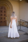 Woman in white midi dress with tie straps, flounce hem.