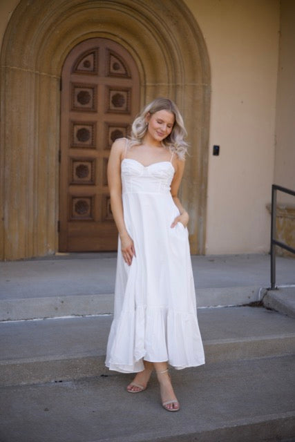 Woman in white midi dress with tie straps, flounce hem.