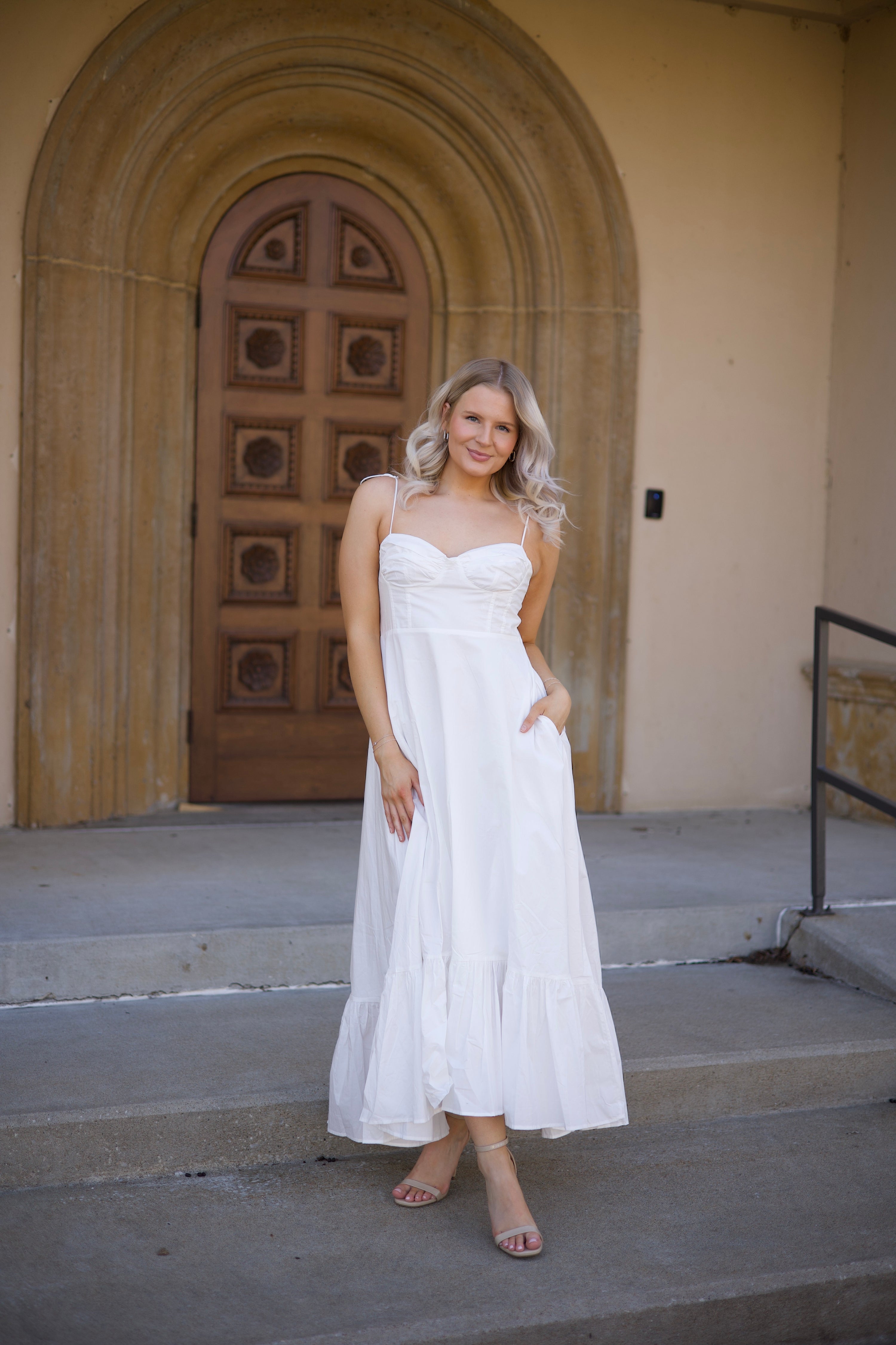 Woman in white midi dress with tie straps, flounce hem.