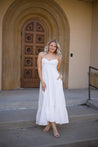 Woman in white midi dress with tie straps, flounce hem.