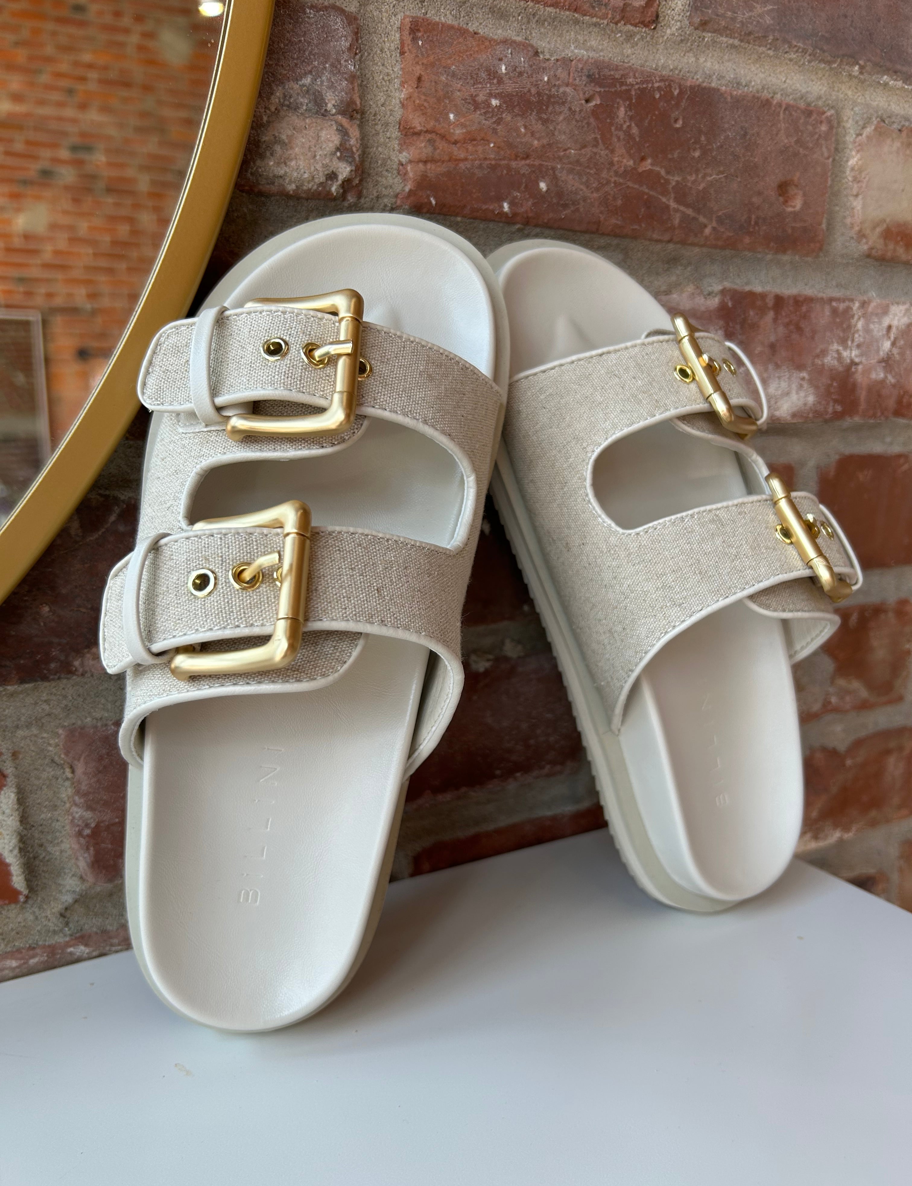 Billini Lilia Linen Sandal with gold double buckles, linen-textured straps, and a cushioned sole for a stylish and comfortable fit.