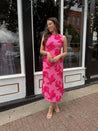 Woman wearing fuchsia floral halter midi dress with pink base and bold floral print