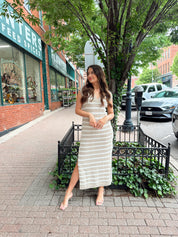 Woman wearing a beige and white striped knit midi dress with a V-neck and side slit