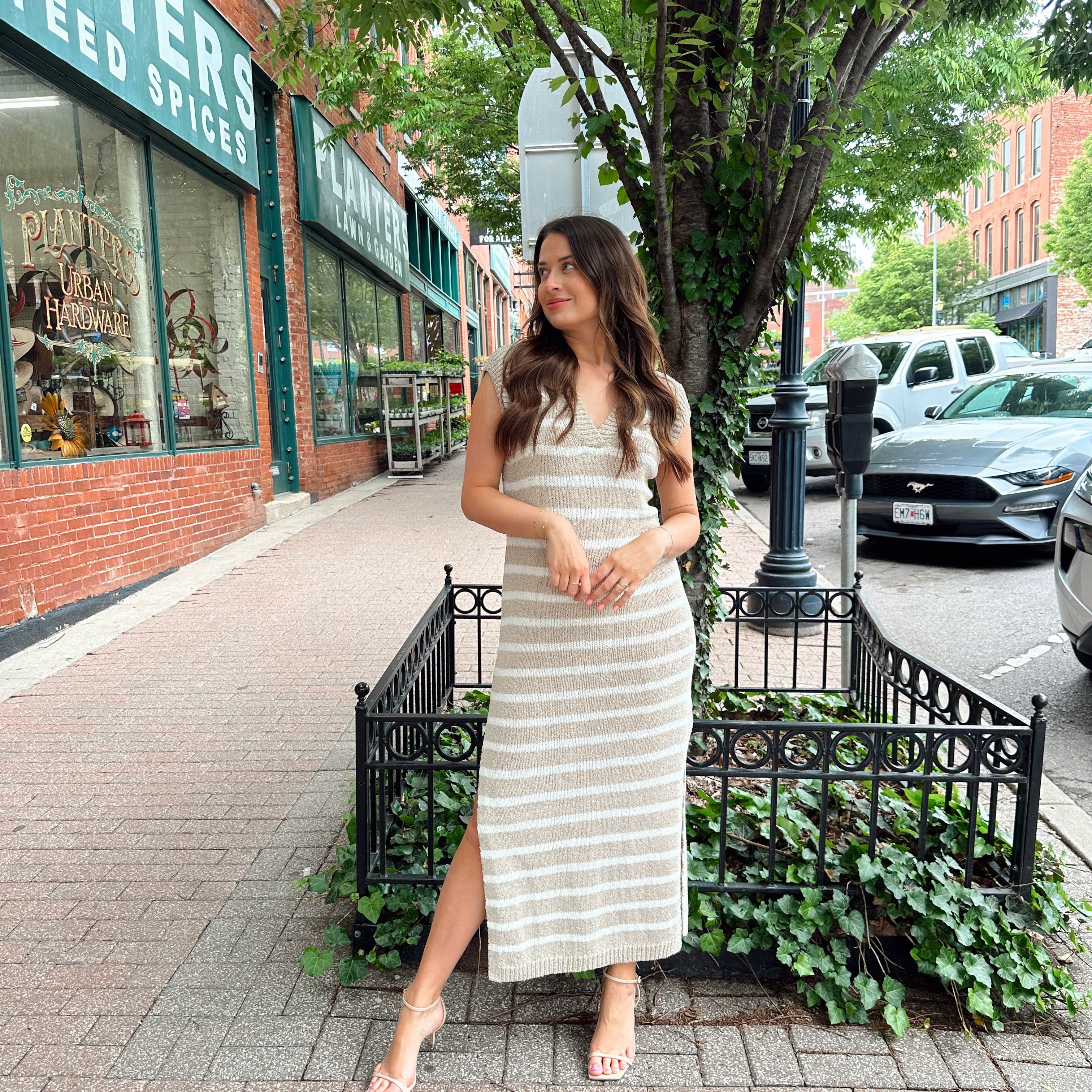 Woman wearing a beige and white striped knit midi dress with a V-neck and side slit