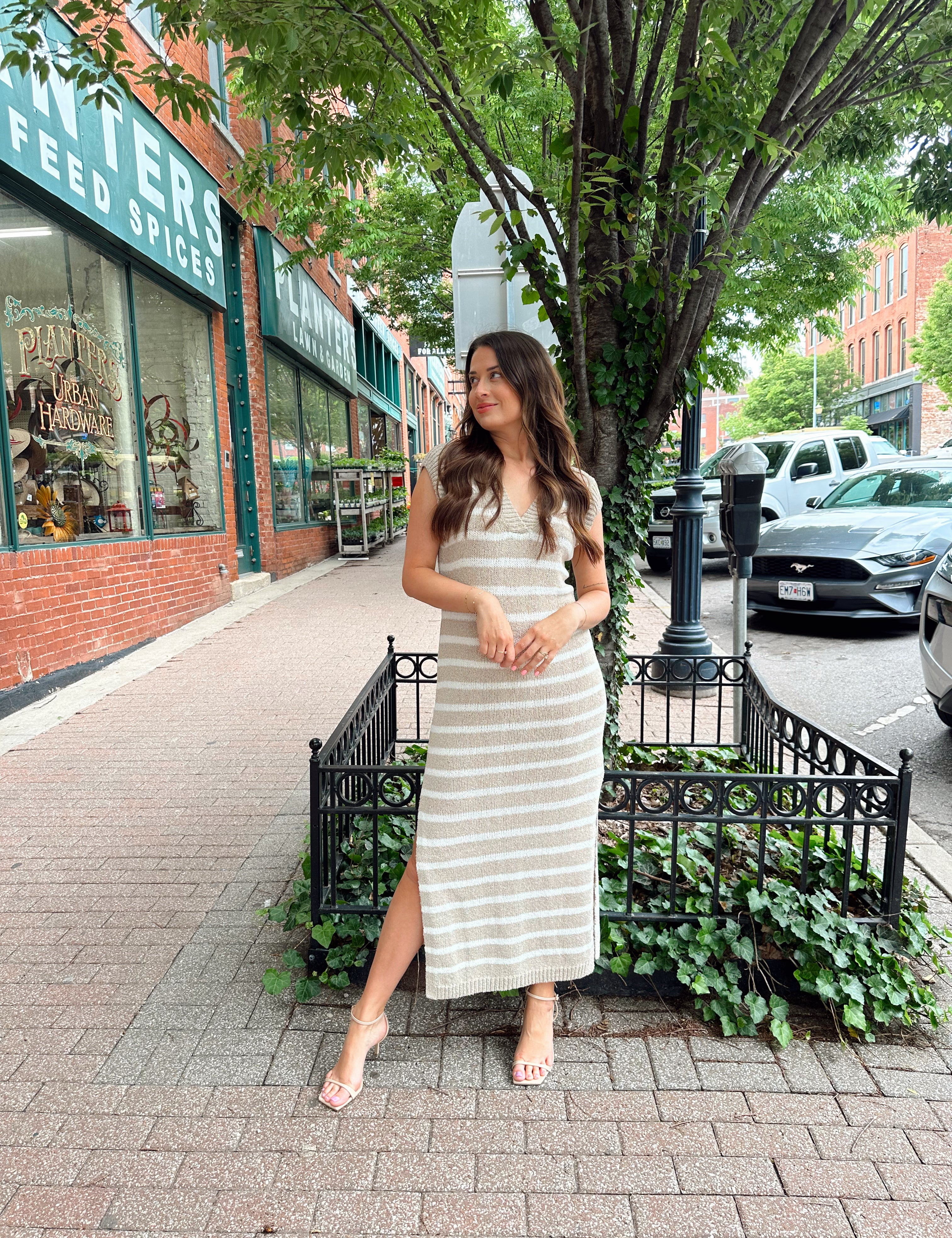 Woman wearing a beige and white striped knit midi dress with a V-neck and side slit