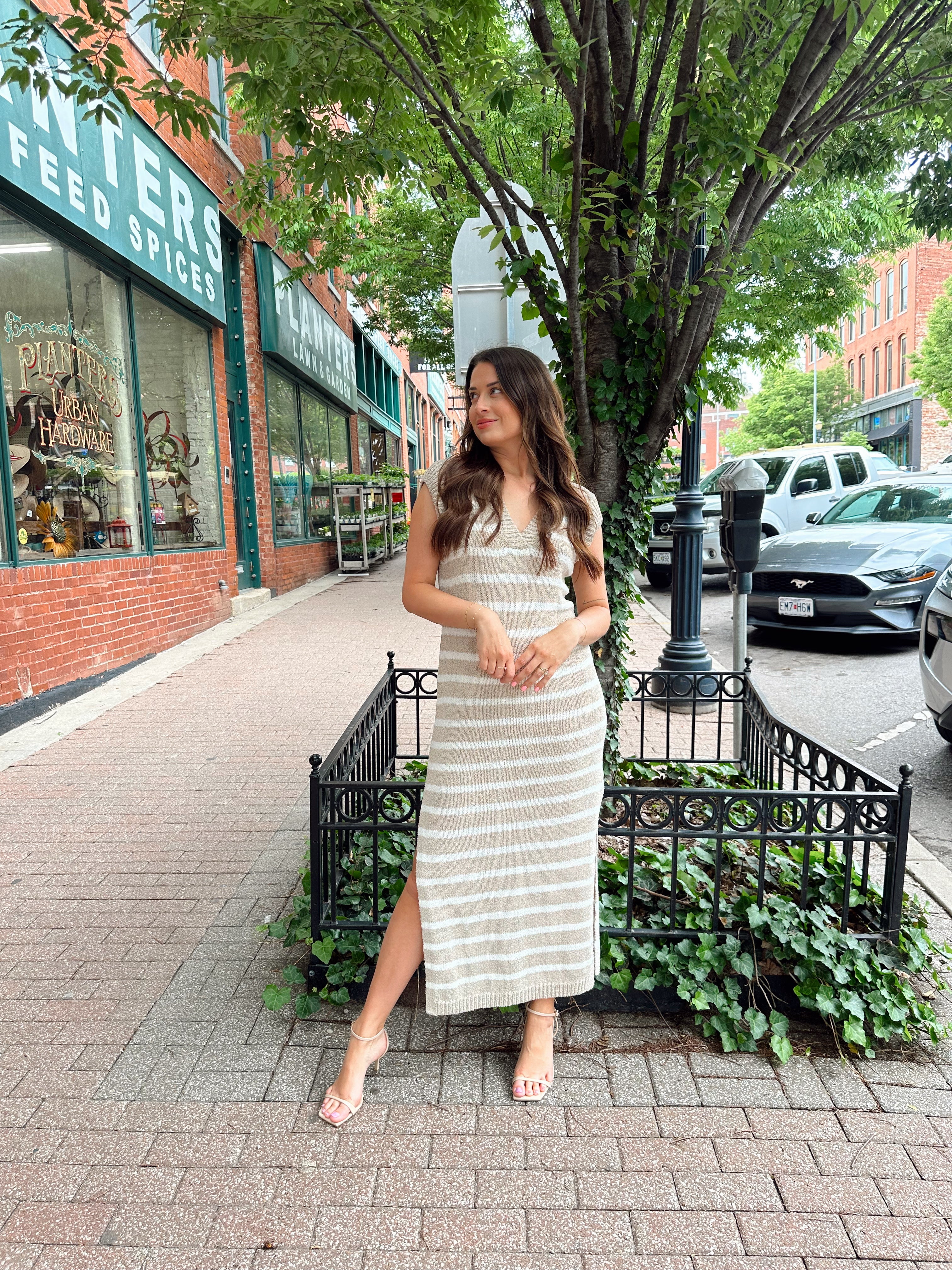 Woman wearing a beige and white striped knit midi dress with a V-neck and side slit