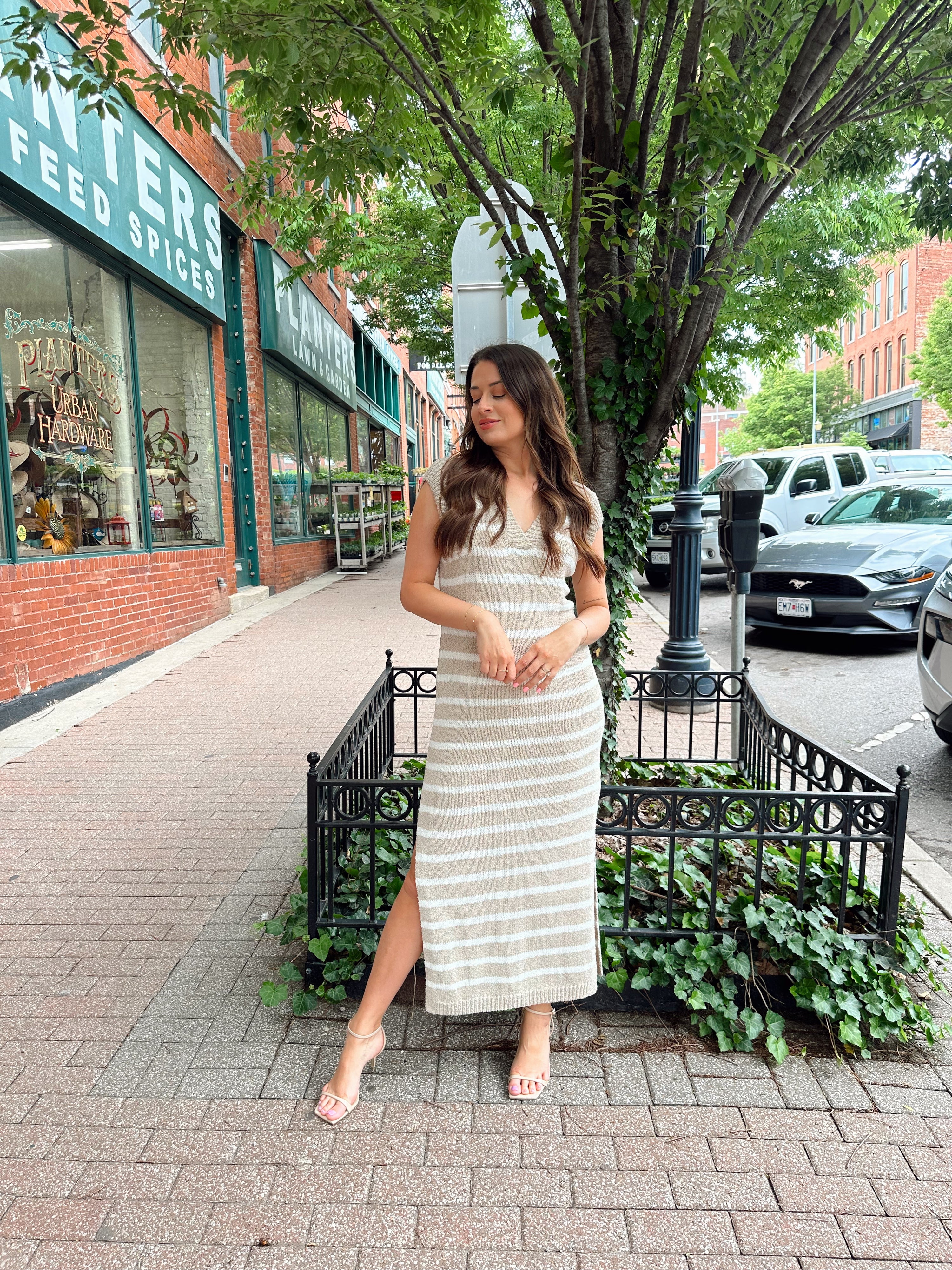 Woman wearing a beige and white striped knit midi dress with a V-neck and side slit