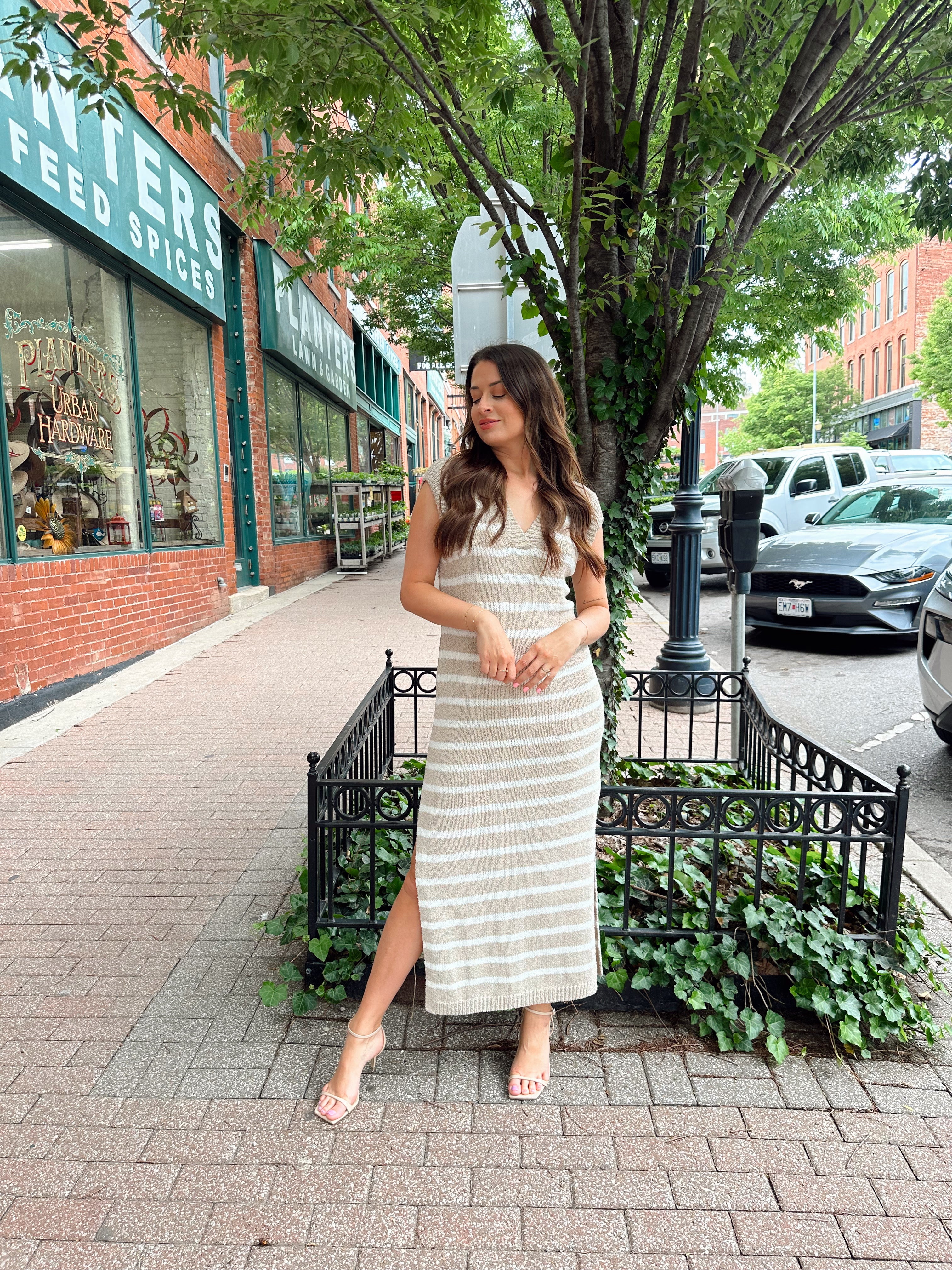 Woman wearing a beige and white striped knit midi dress with a V-neck and side slit