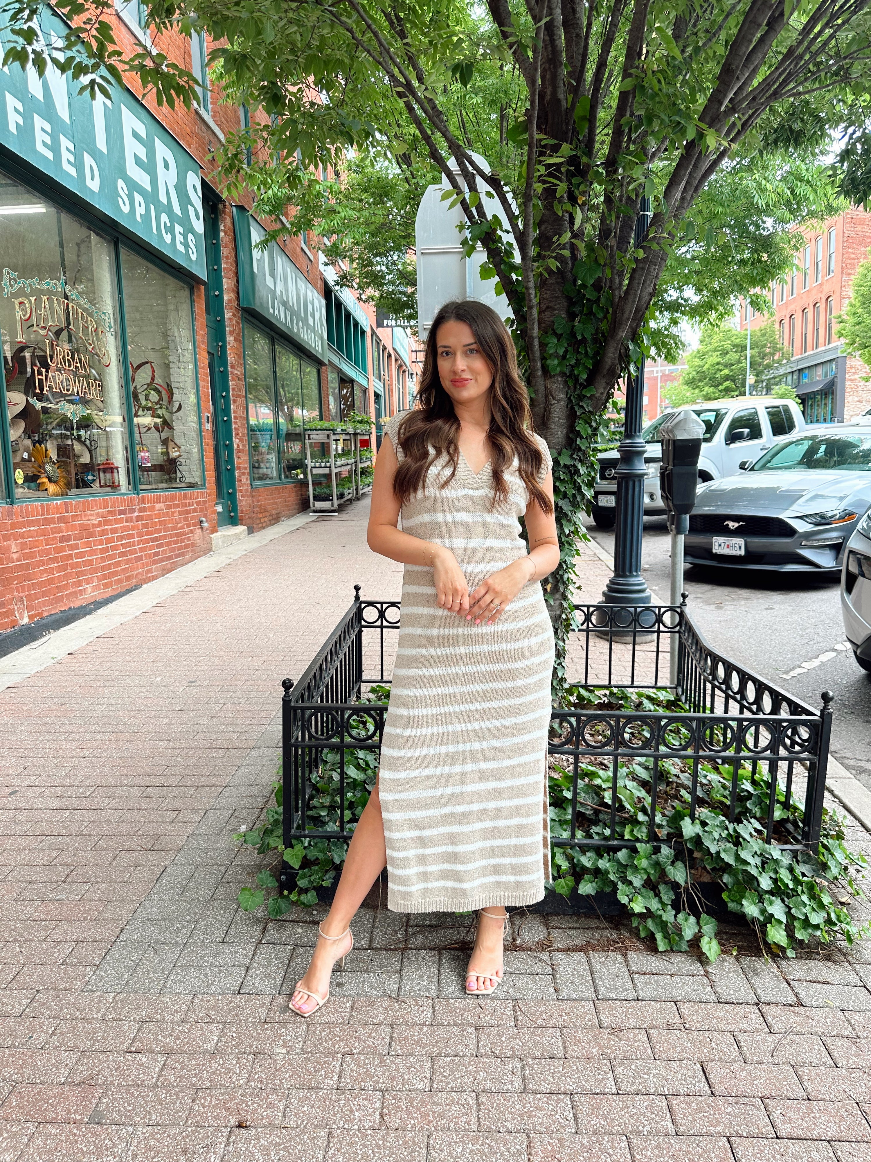 Woman wearing a beige and white striped knit midi dress with a V-neck and side slit